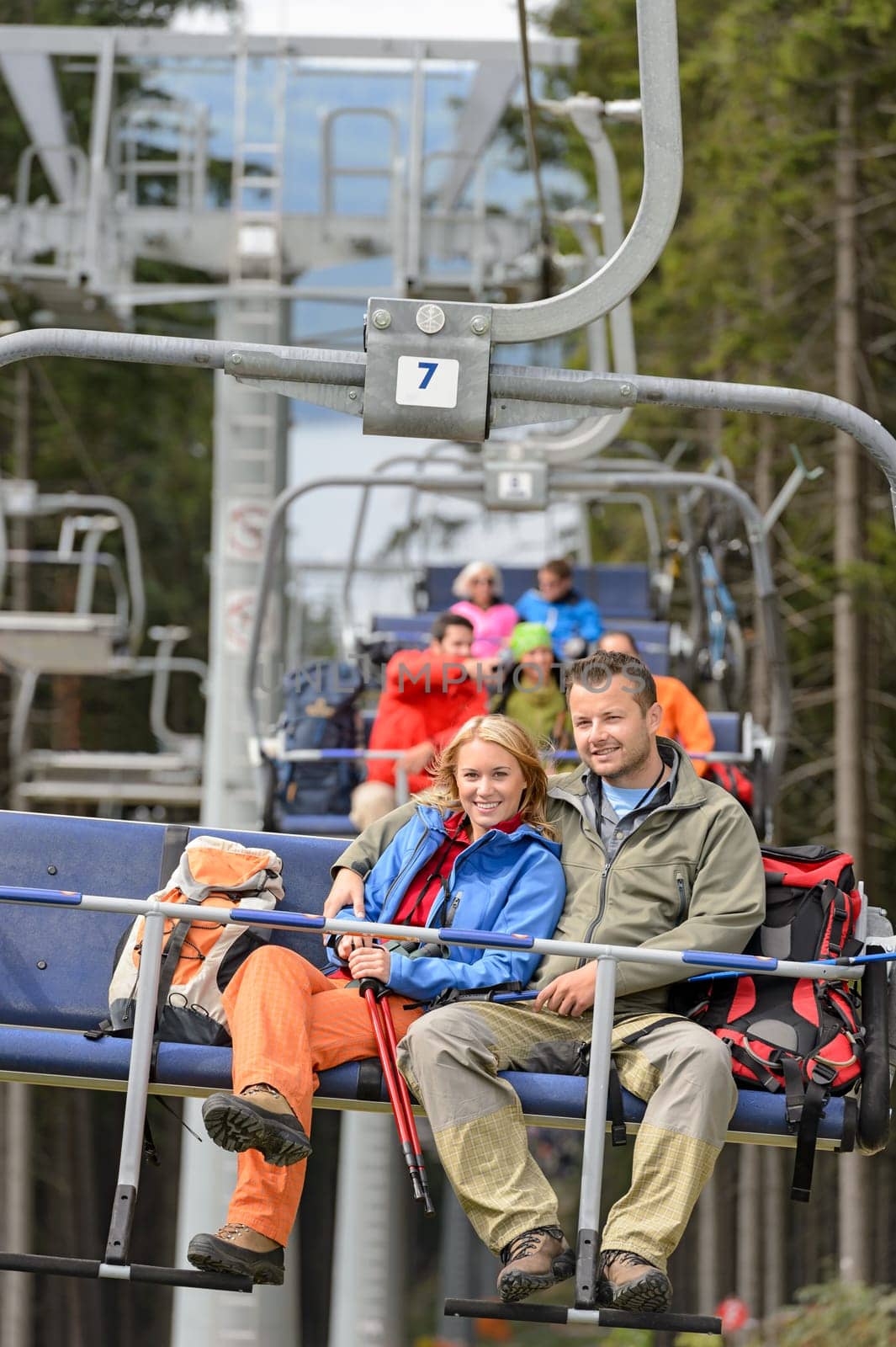 Lovely hiker couple sitting together on chairlift