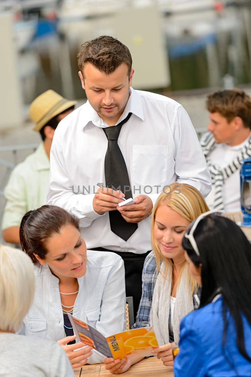 Women customers ordering from waiter at sidewalk restaurant