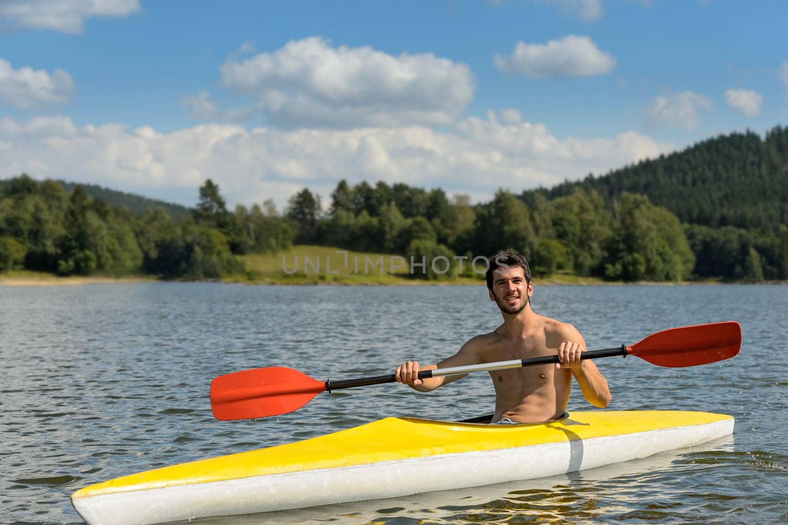 Young sportsman kayaking on sunny day on lake