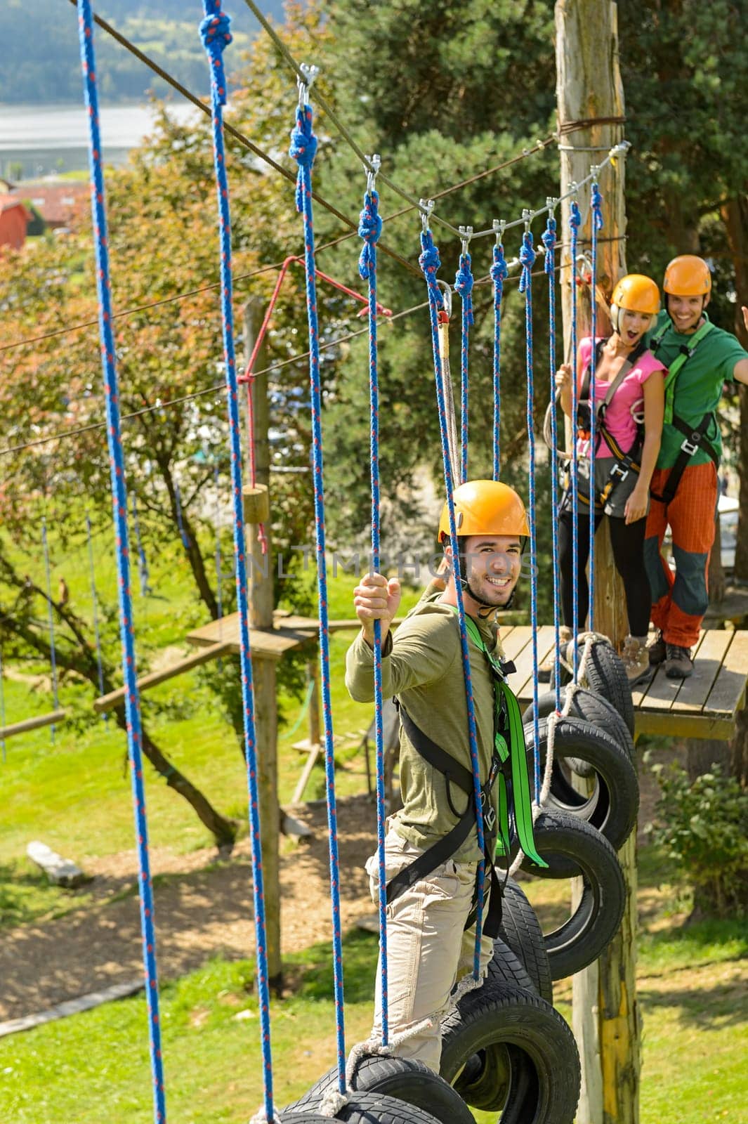 Young friends having fun in adventure park in helmets