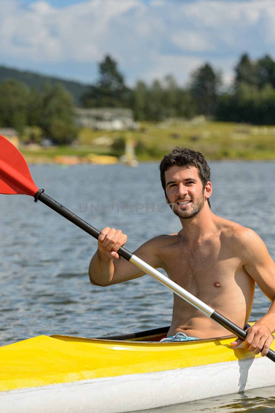 Young muscular sportsman kayaking in the sunshine