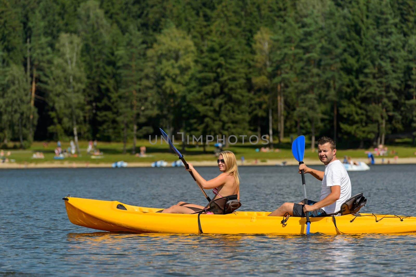 Young couple on summer weekend kayaking on pond