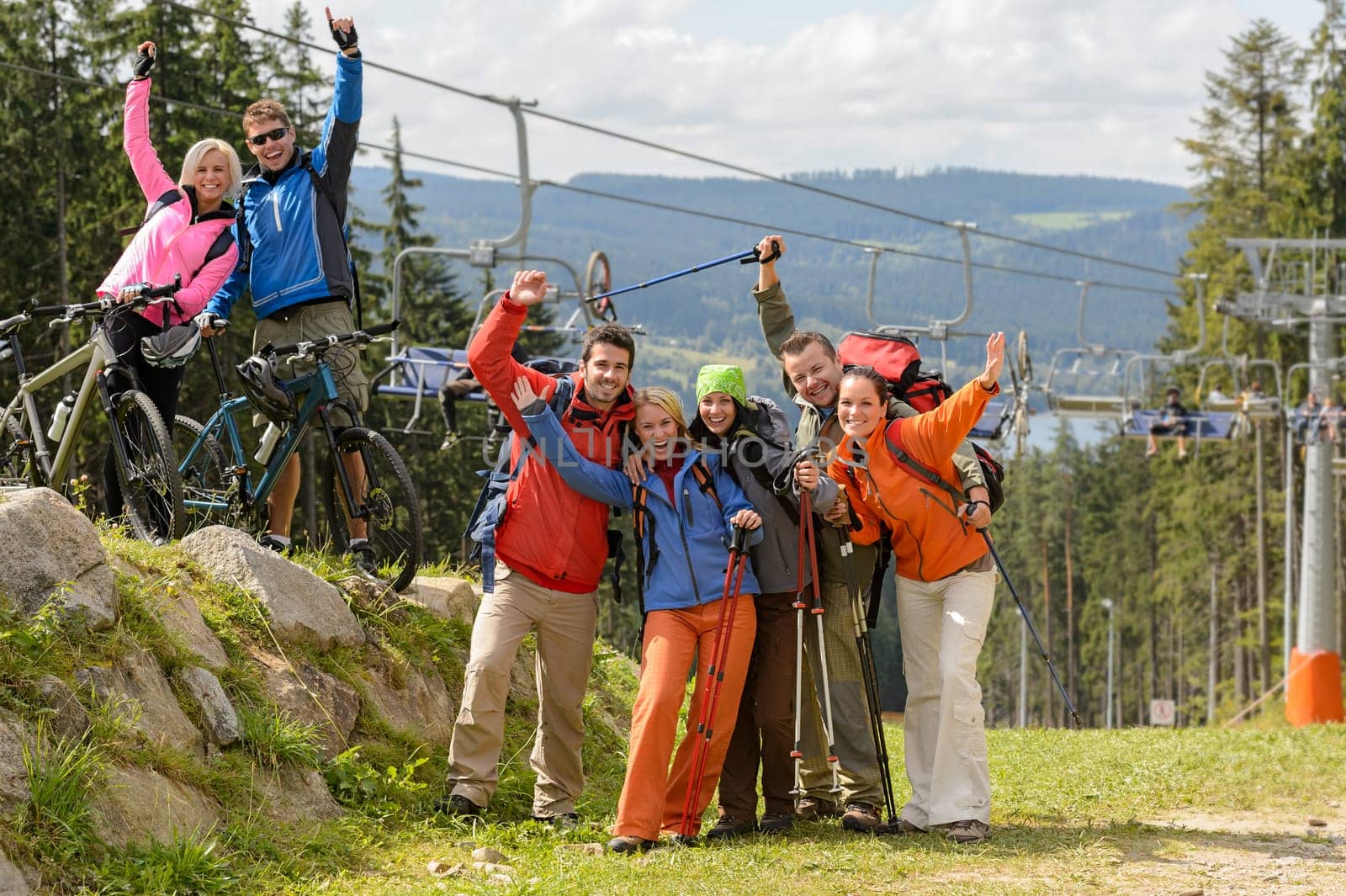 Cheering hikers with raised arms at peak of the mountain