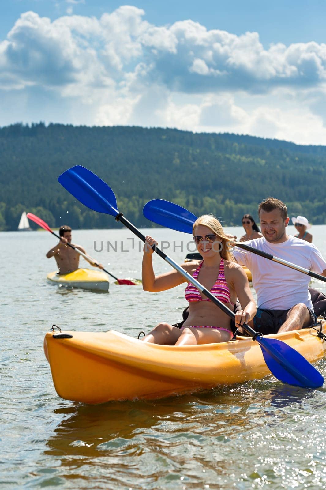 Young friends kayaking in summertime on lake holiday