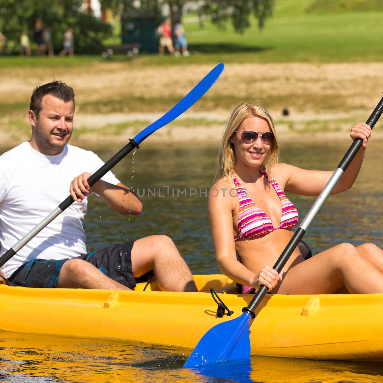 Young couple kayaking summertime in the sunshine vacation