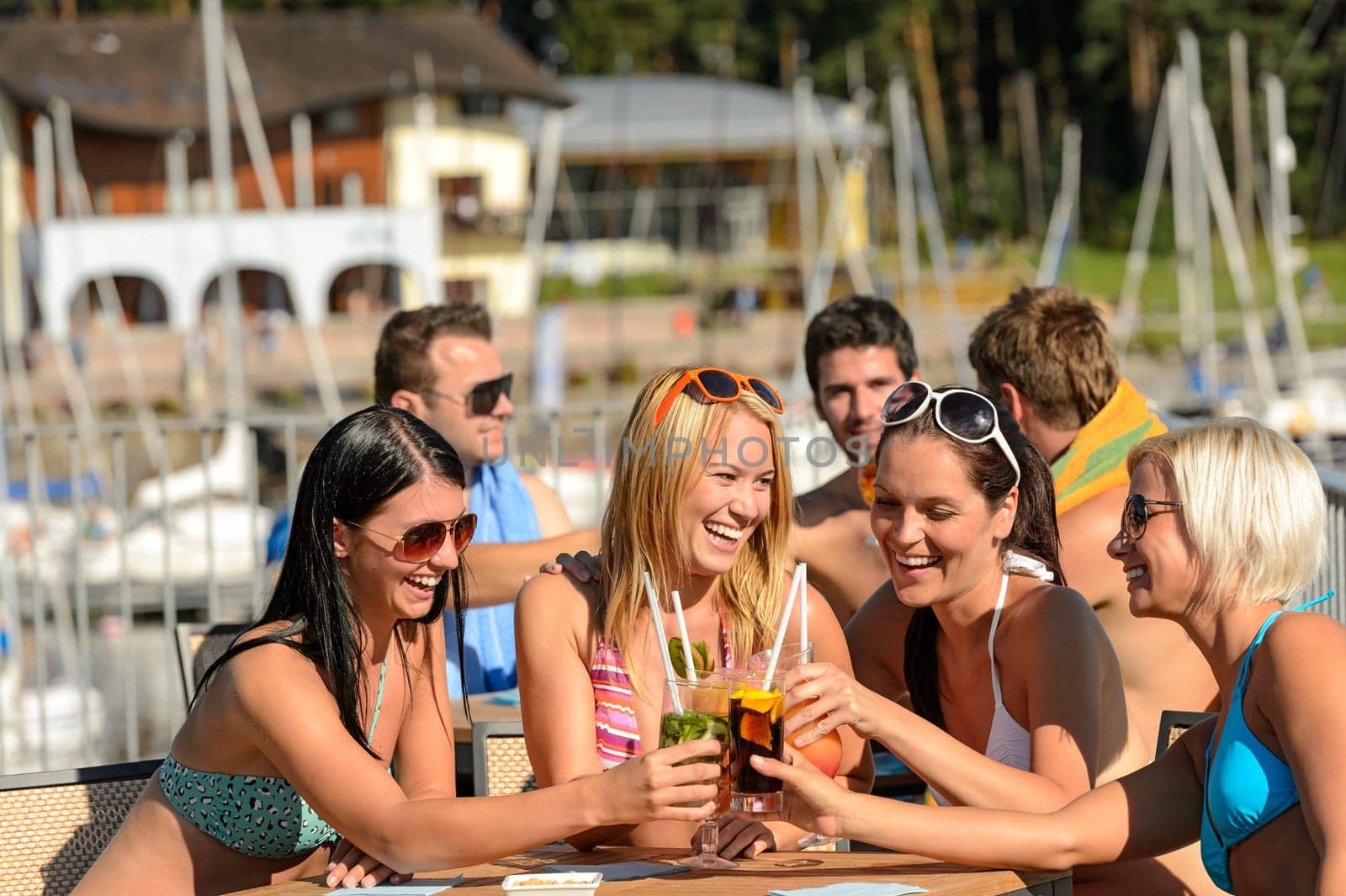 Beautiful women in bikinis toasting with cocktails at beach