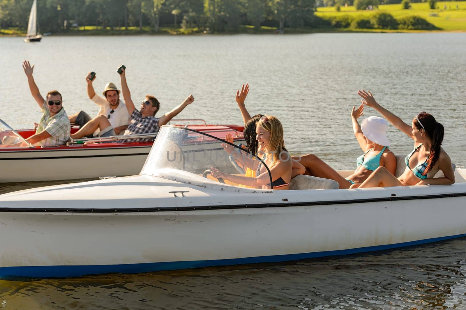 Waving young friends sitting in motorboats enjoying summertime