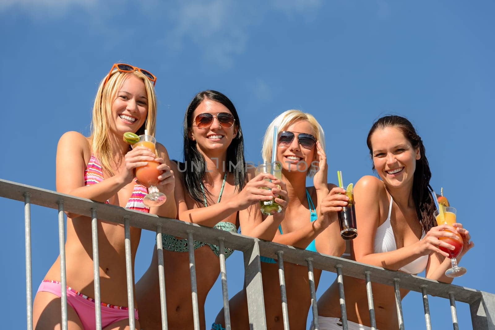 Beautiful women in bikinis and sunglasses smiling with drinks