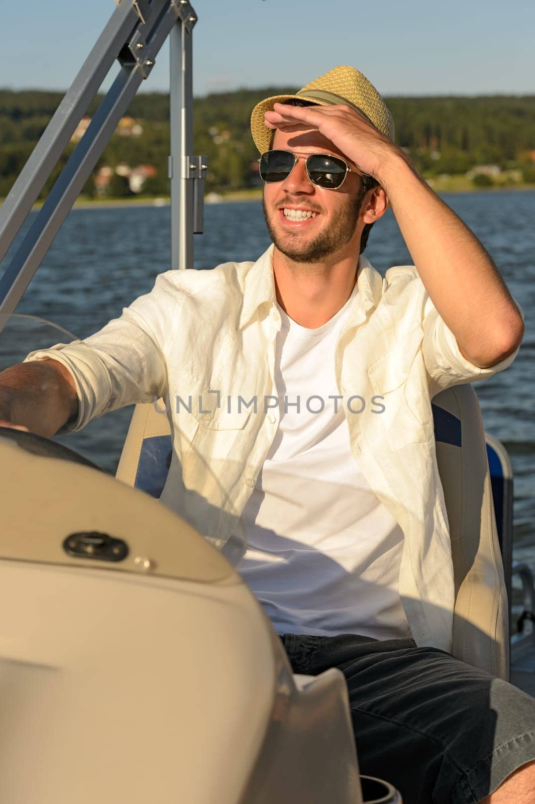 Man in sunglasses and straw hat navigating boat sunny day
