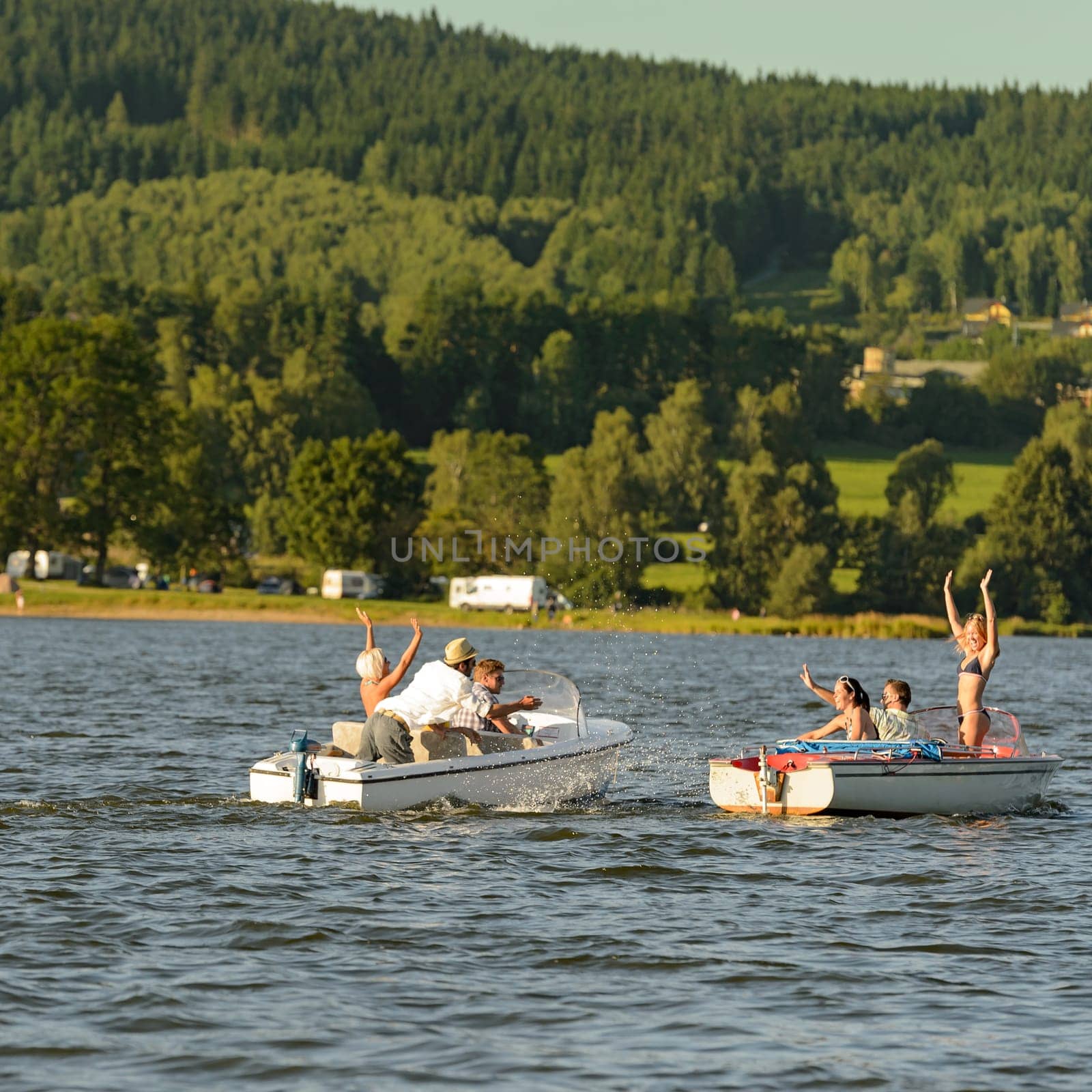 Young people having fun on motorboats on lake summertime