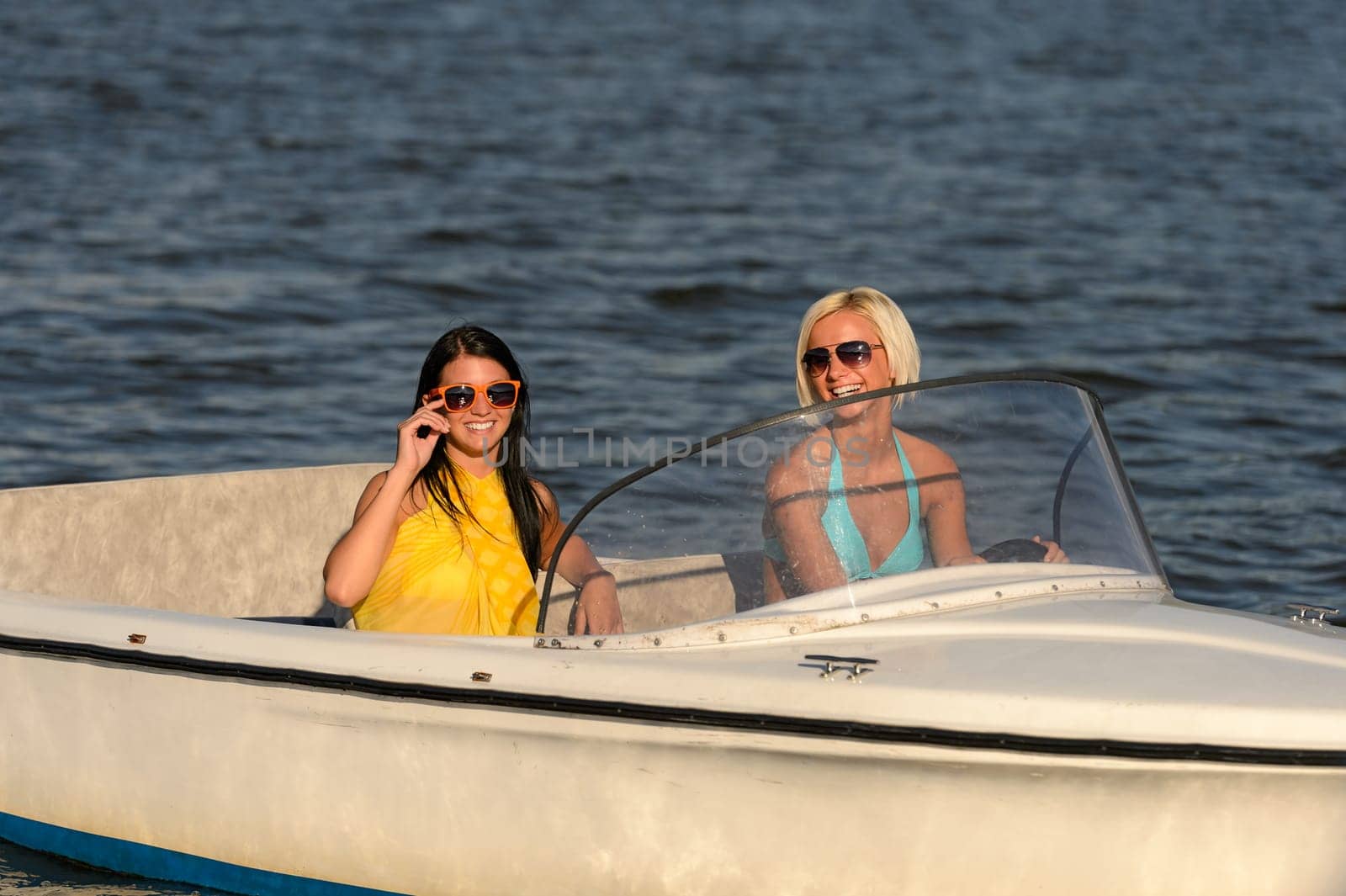 Young women in sunglasses sitting in motorboat driving