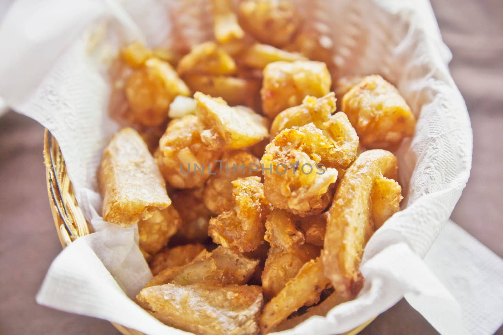 Horizontal capture of various styles and type of potato deep fried and presented in on a serviette in a basket