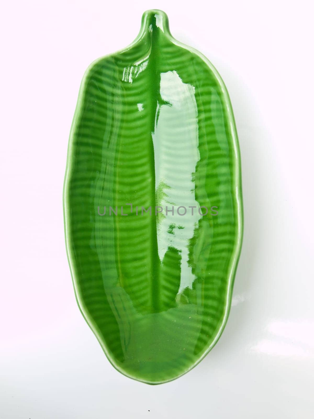 A green banana leaf  ceramic dish isolated on white background