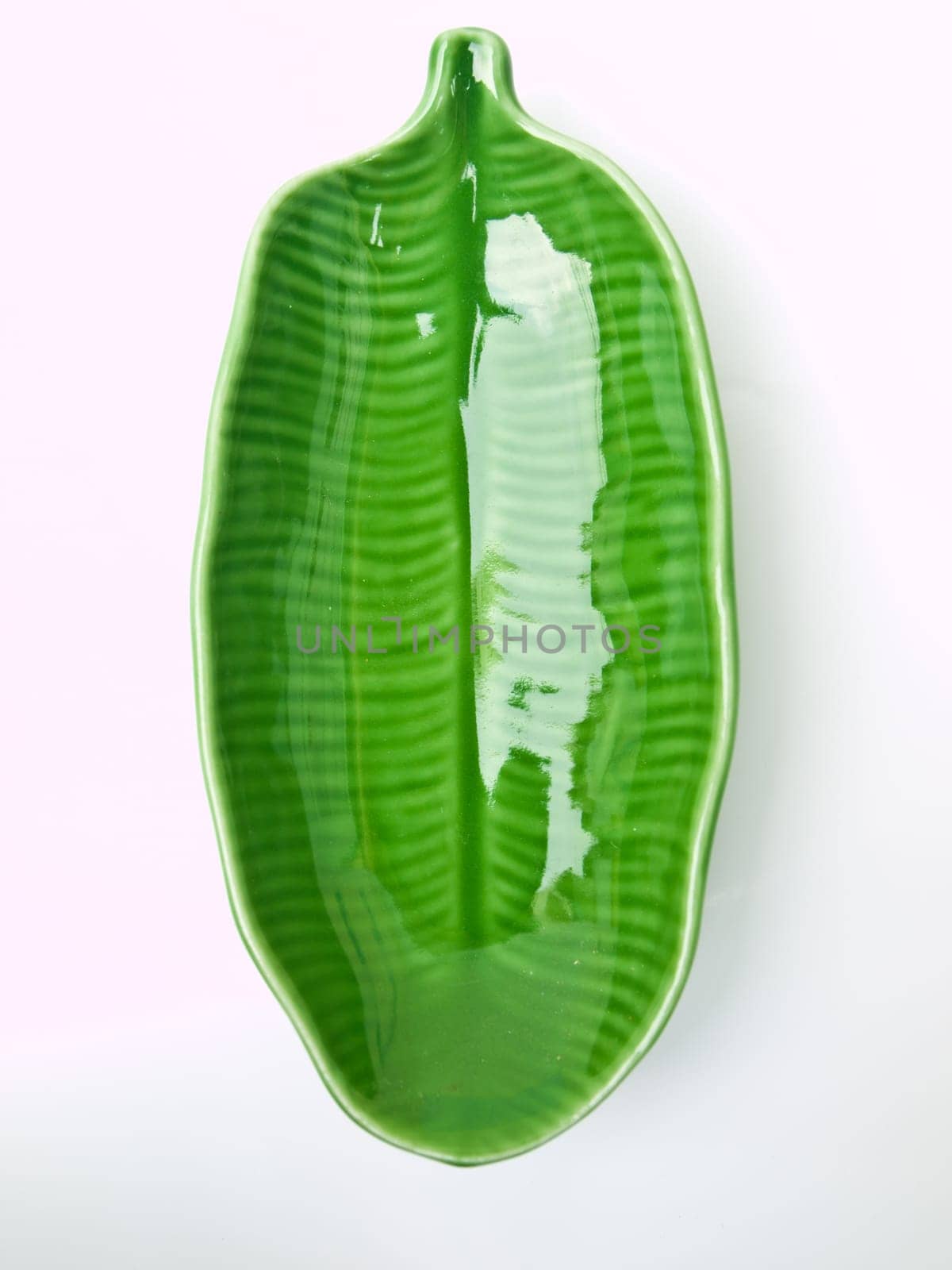 A green banana leaf  ceramic dish isolated on white background