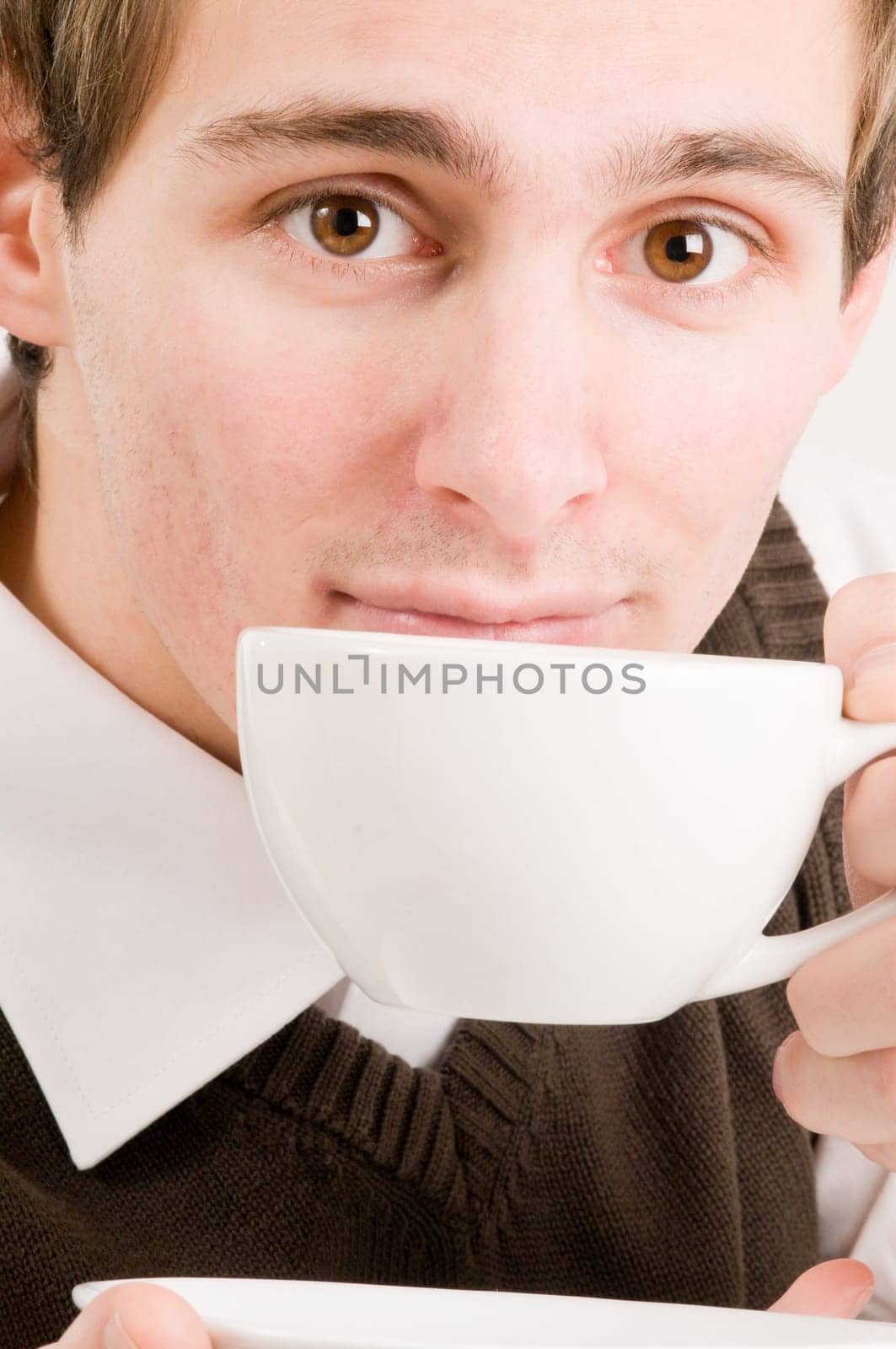 Side head and shoulders shot of a young man drinking from a white cup against a white background