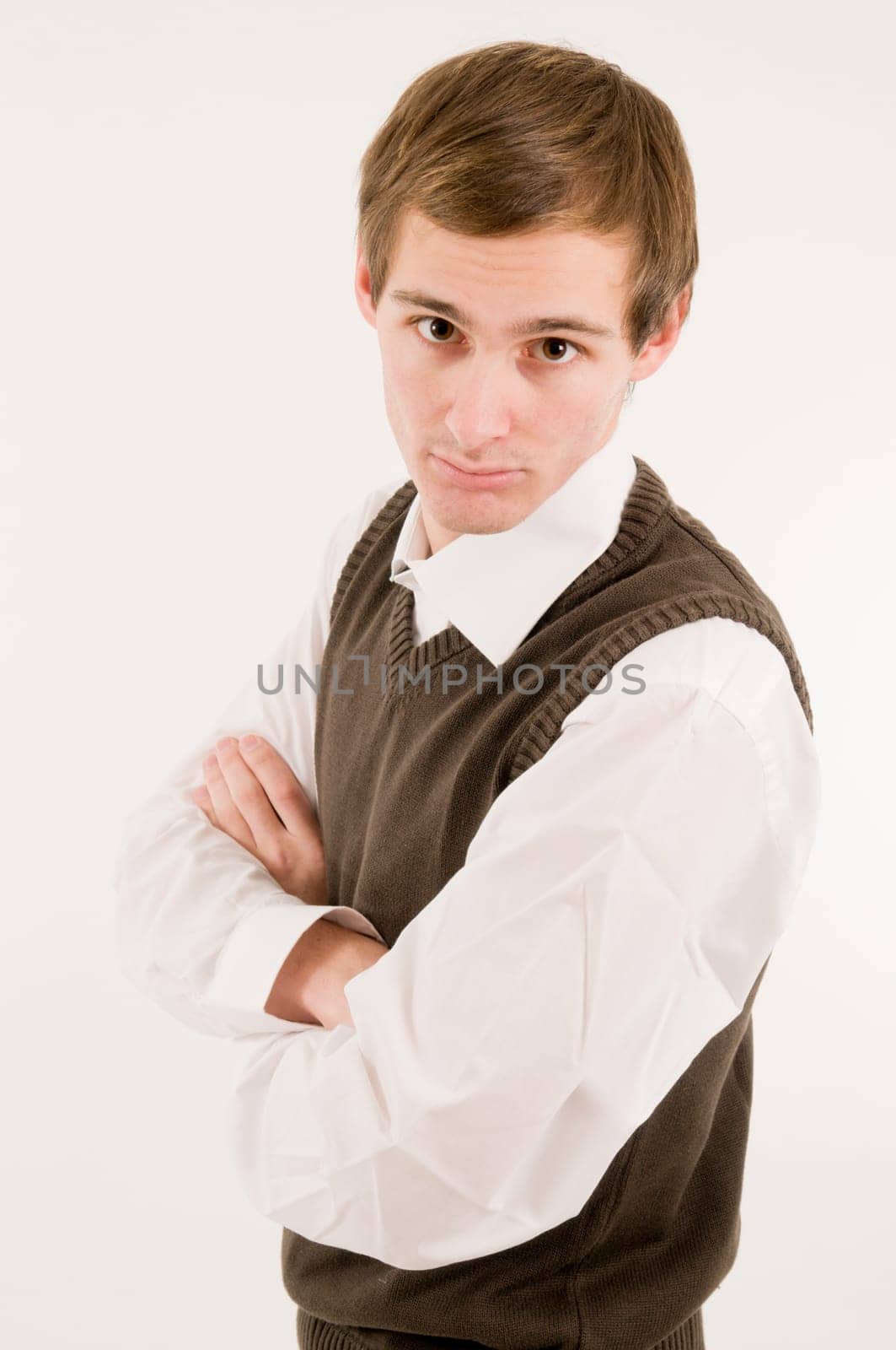 Side torso shot of a young man in a white shirt and brown westover with crossed arms looking provocatively towards the camera