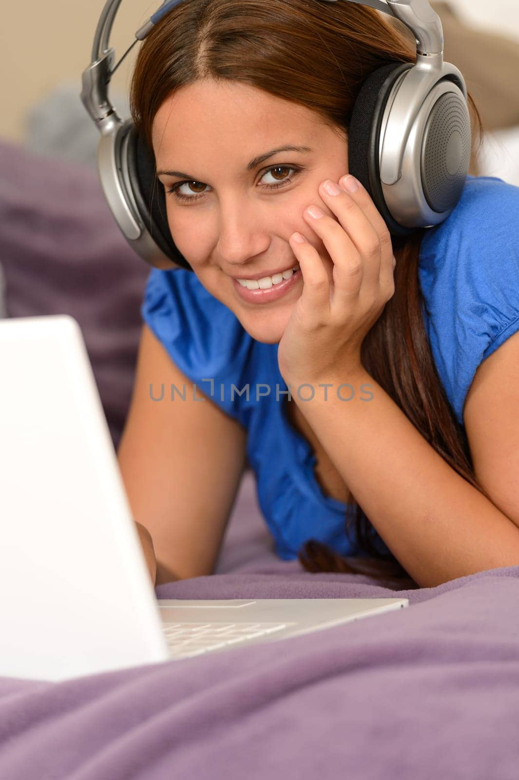 Young smiling girl using laptop and listening music with headphones