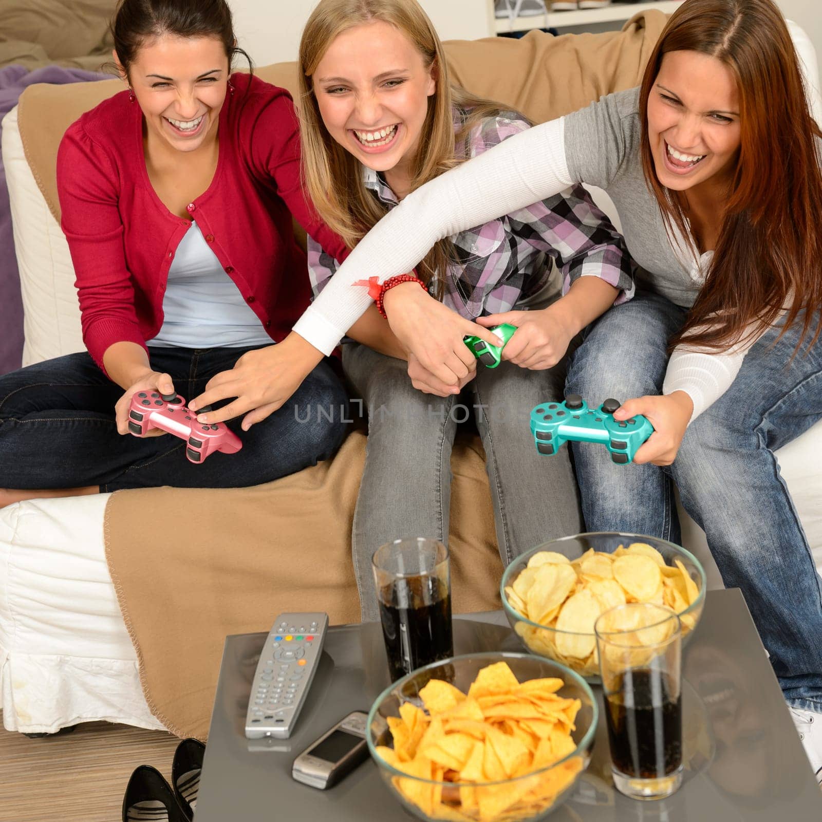 Laughing teenage girls playing with video game with consoles