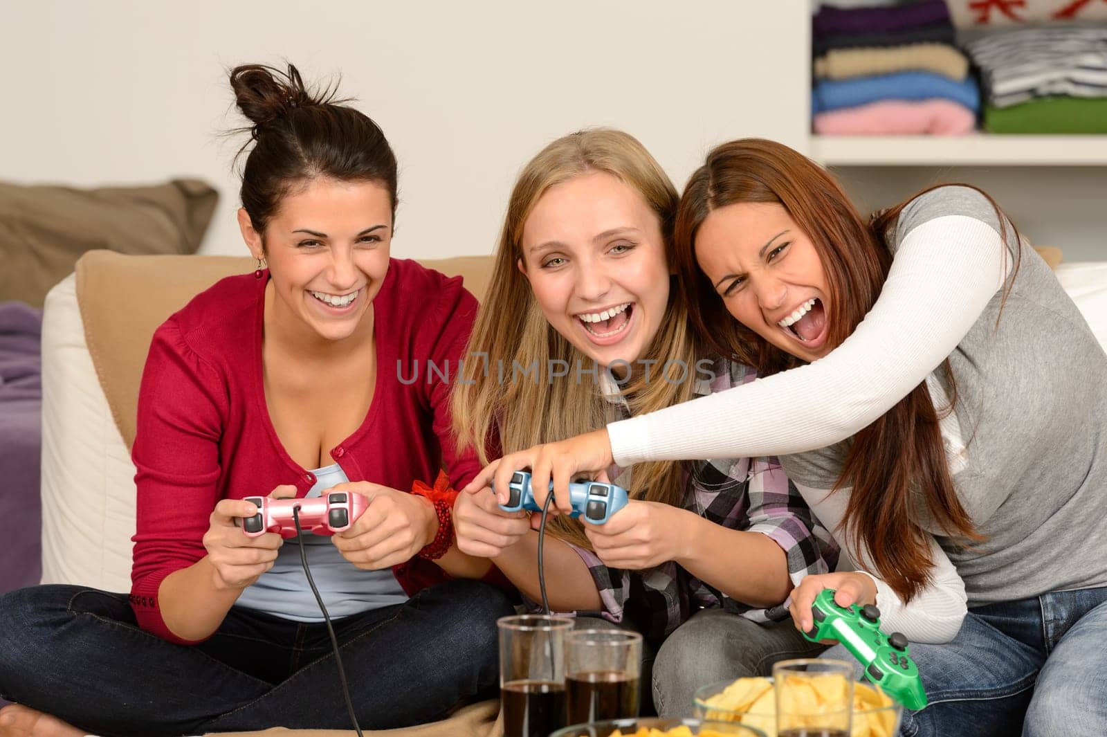 Laughing young girls playing with video games at home