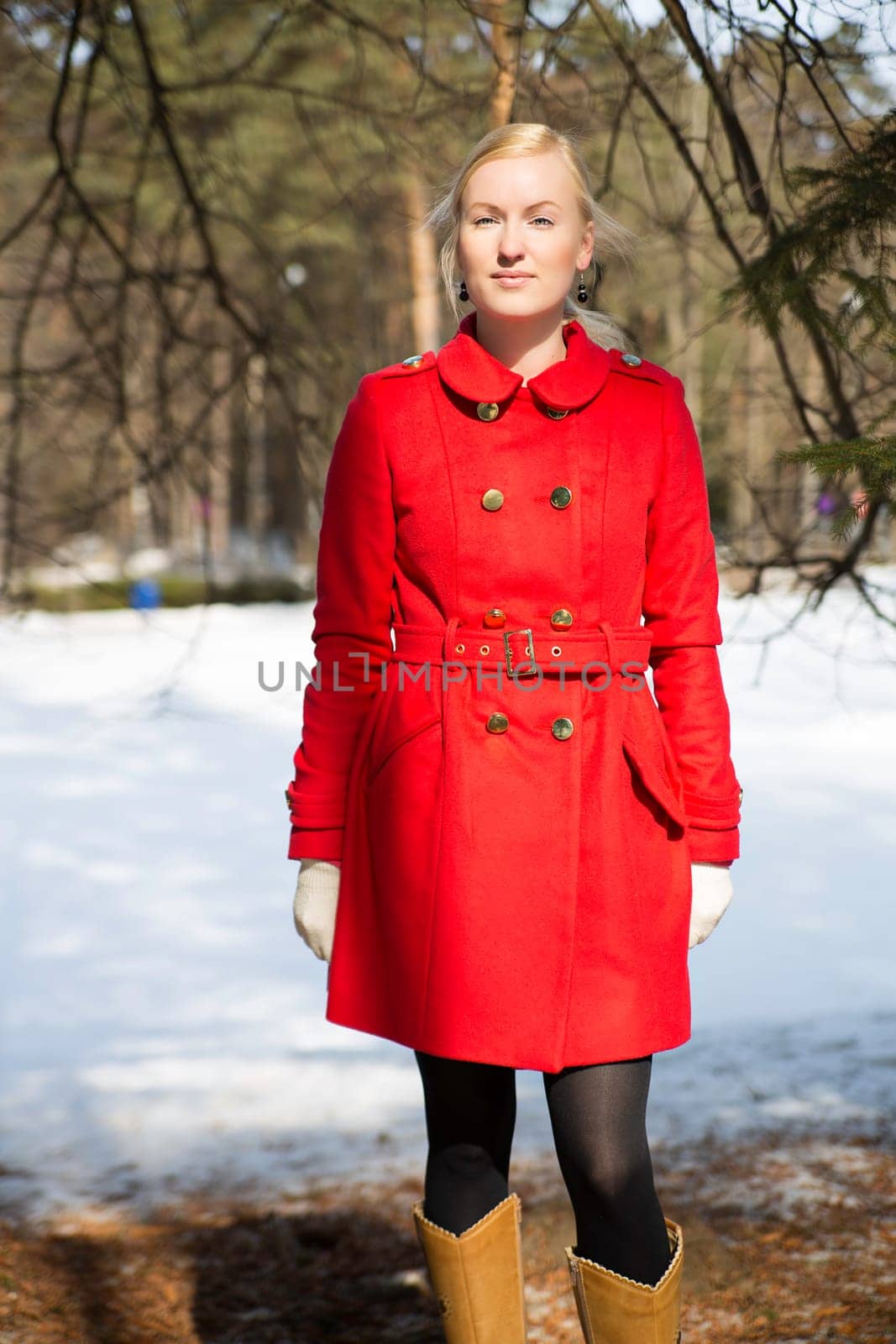 Young woman in red coat under spruce tops