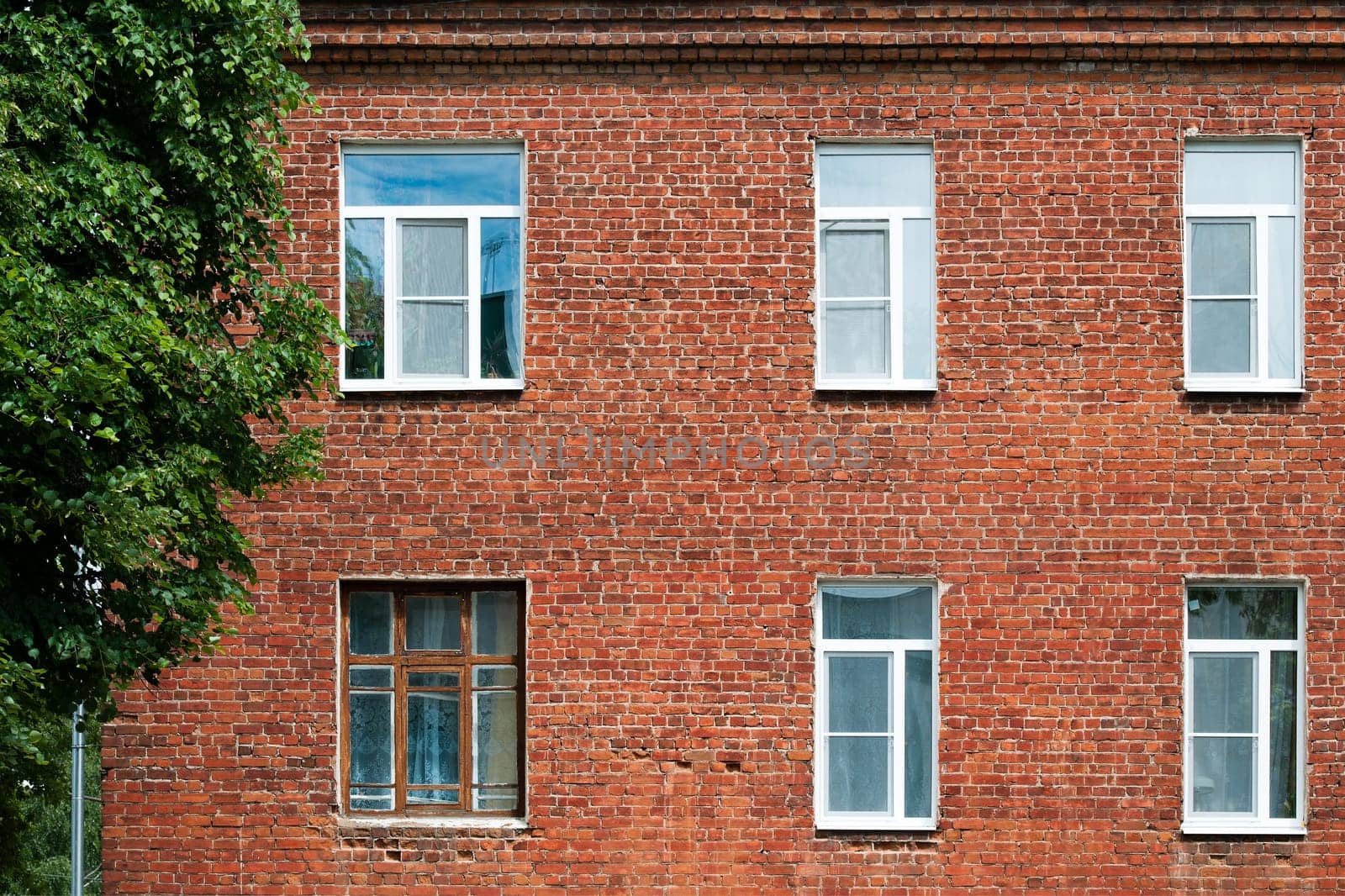 House of red brick with windows and tree in the frame.