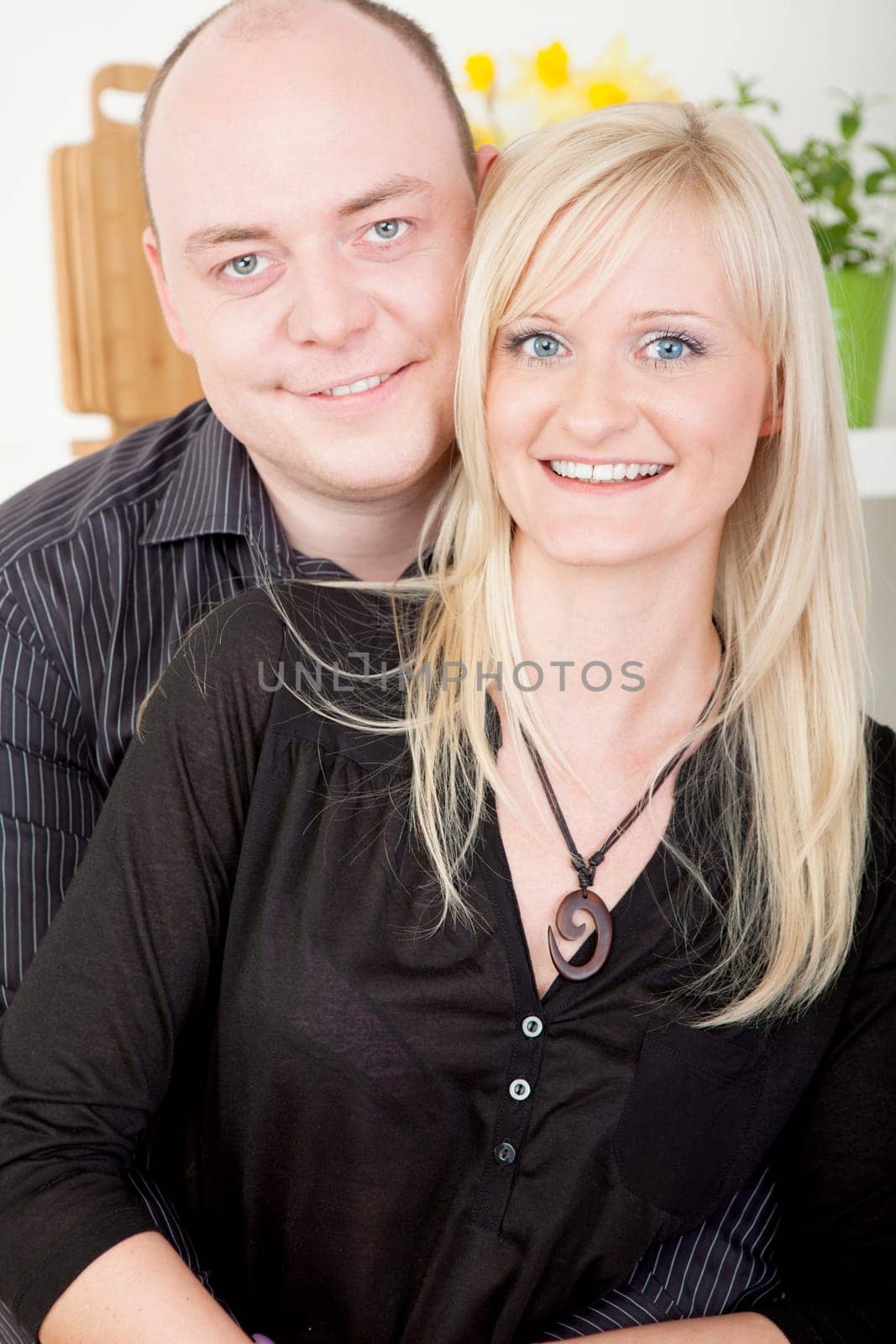 Attractive married couple standing close together posing for a portrait looking at the camera and smiling