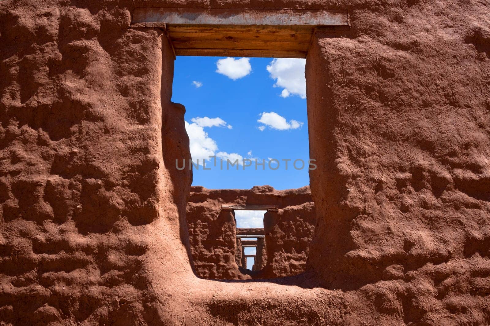 View through windows in a row of ruins of red adobe style buildings