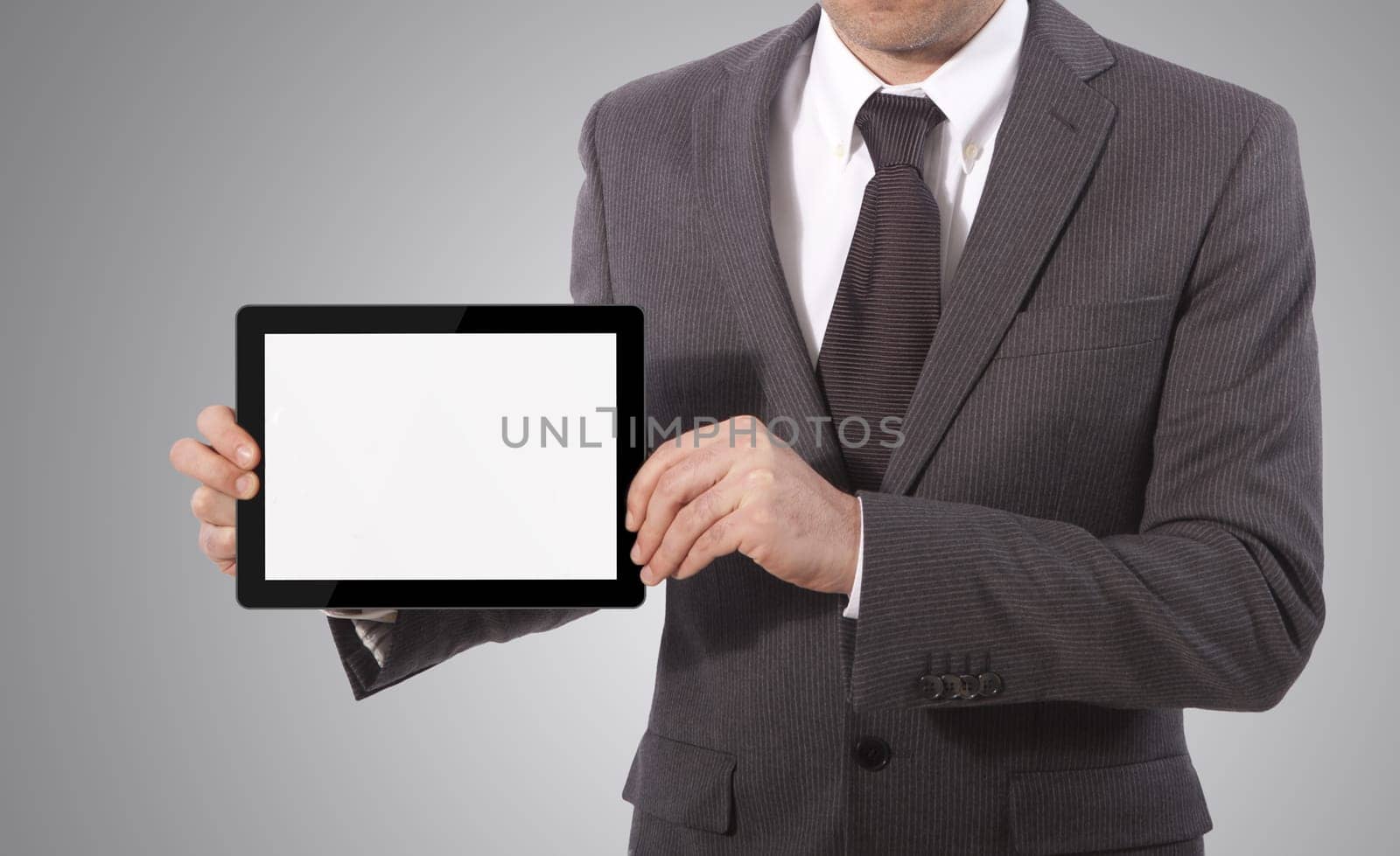 business man with blank touch tablet in hands, grey background