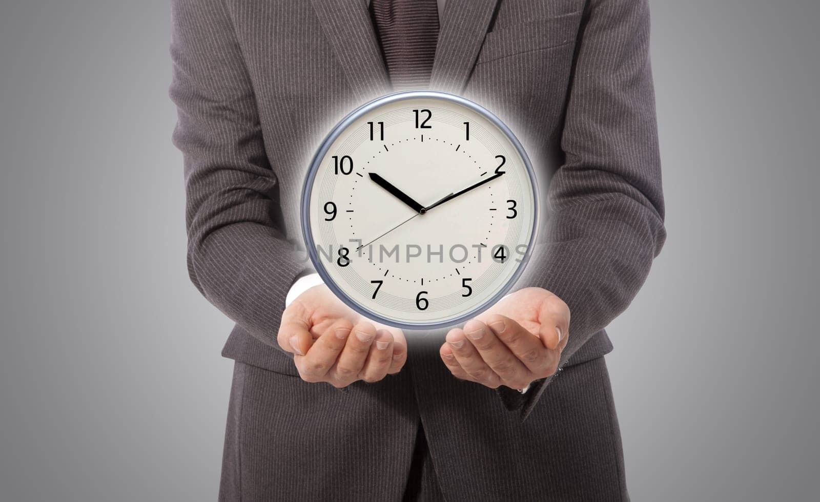 business man with wall clock on his hand, grey background