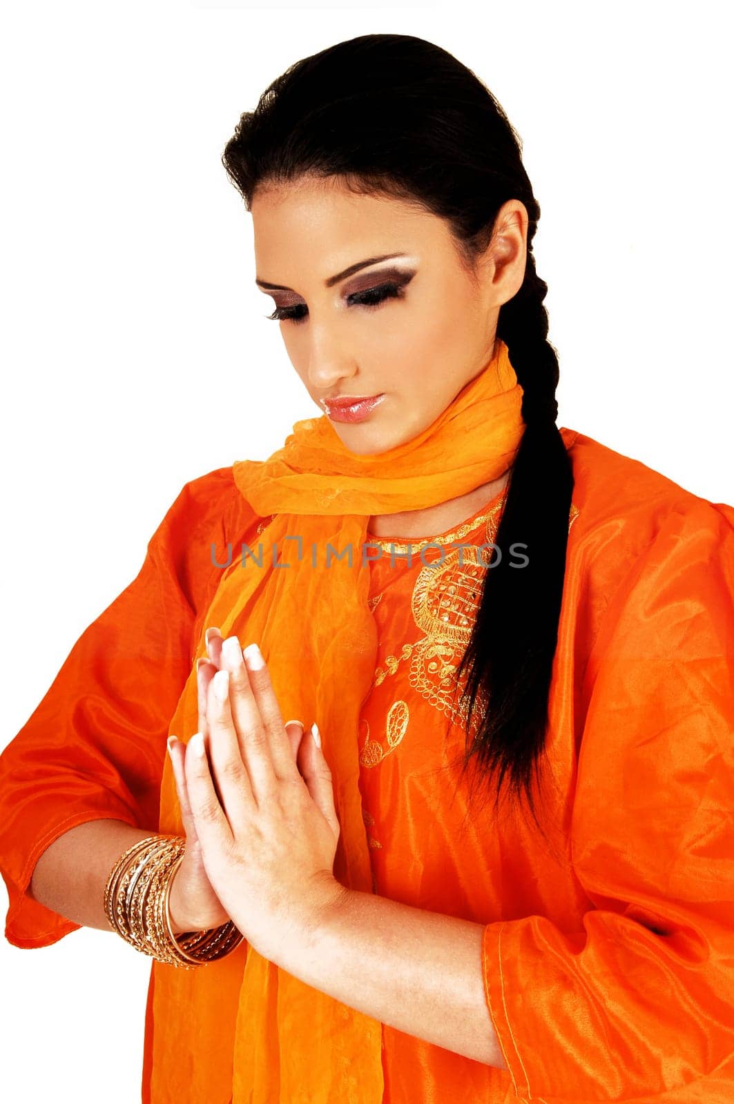 A beautiful east indian teen girl in her traditional silk dress and her long black hair standing for white background with folded hands praying.
