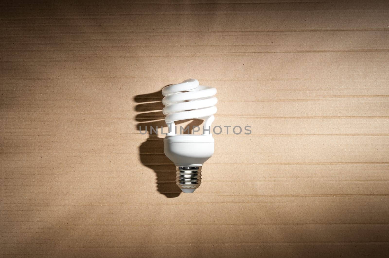 white fluorescent light bulb with strong shadow against cardboard background