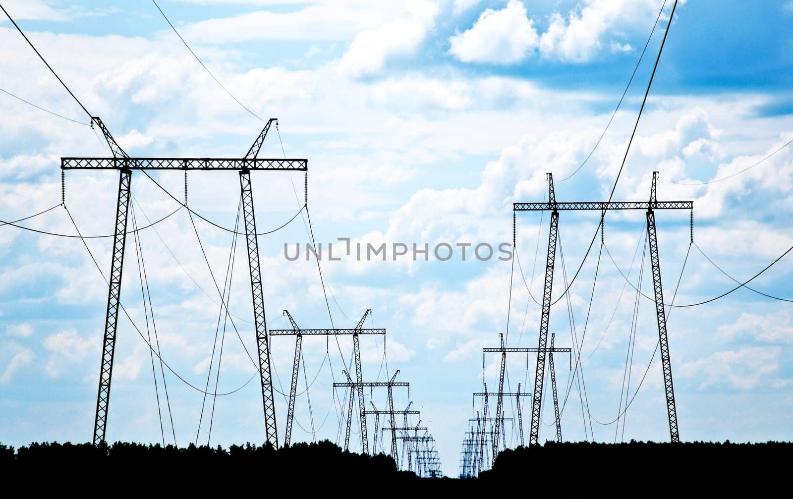 power grid pylons against blue cloudy sky