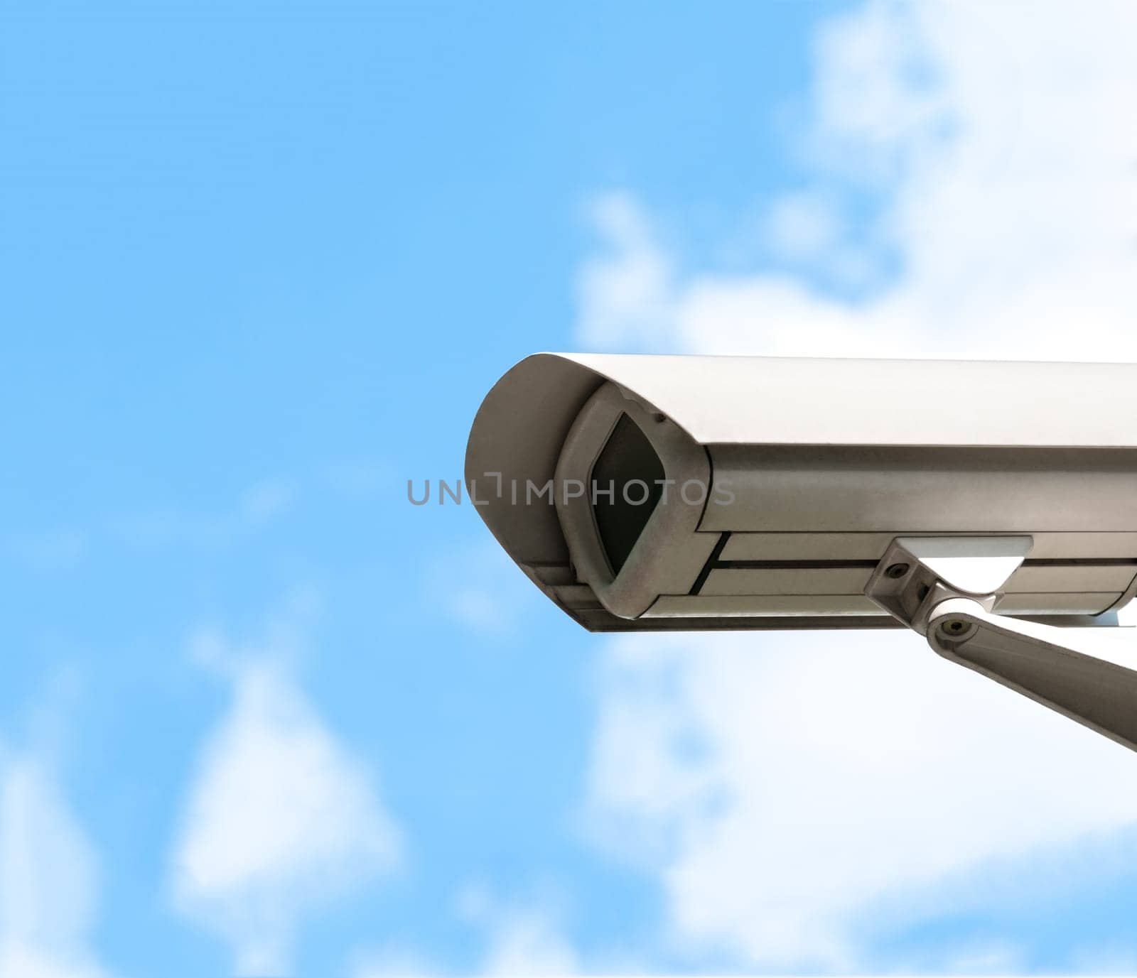 White security camera. Blue cloudy sky in background. A lot of copy space.