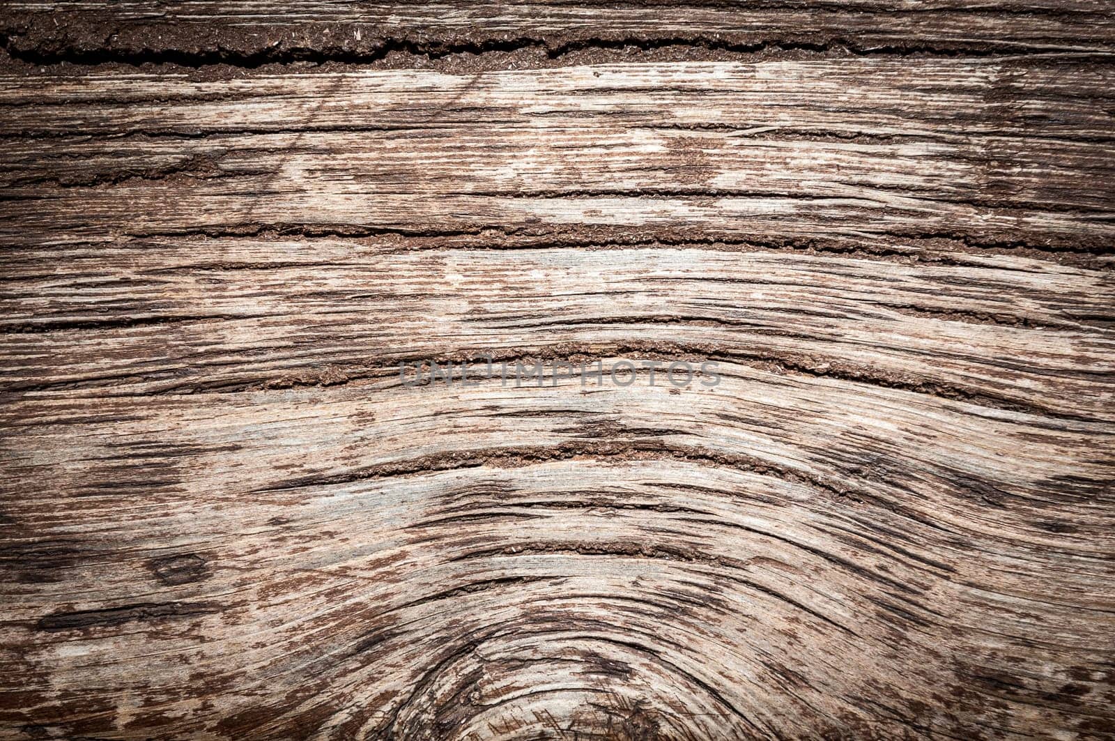 Old wood background with cracks and lines. Light in the middle with space for copy, dark at the sides.