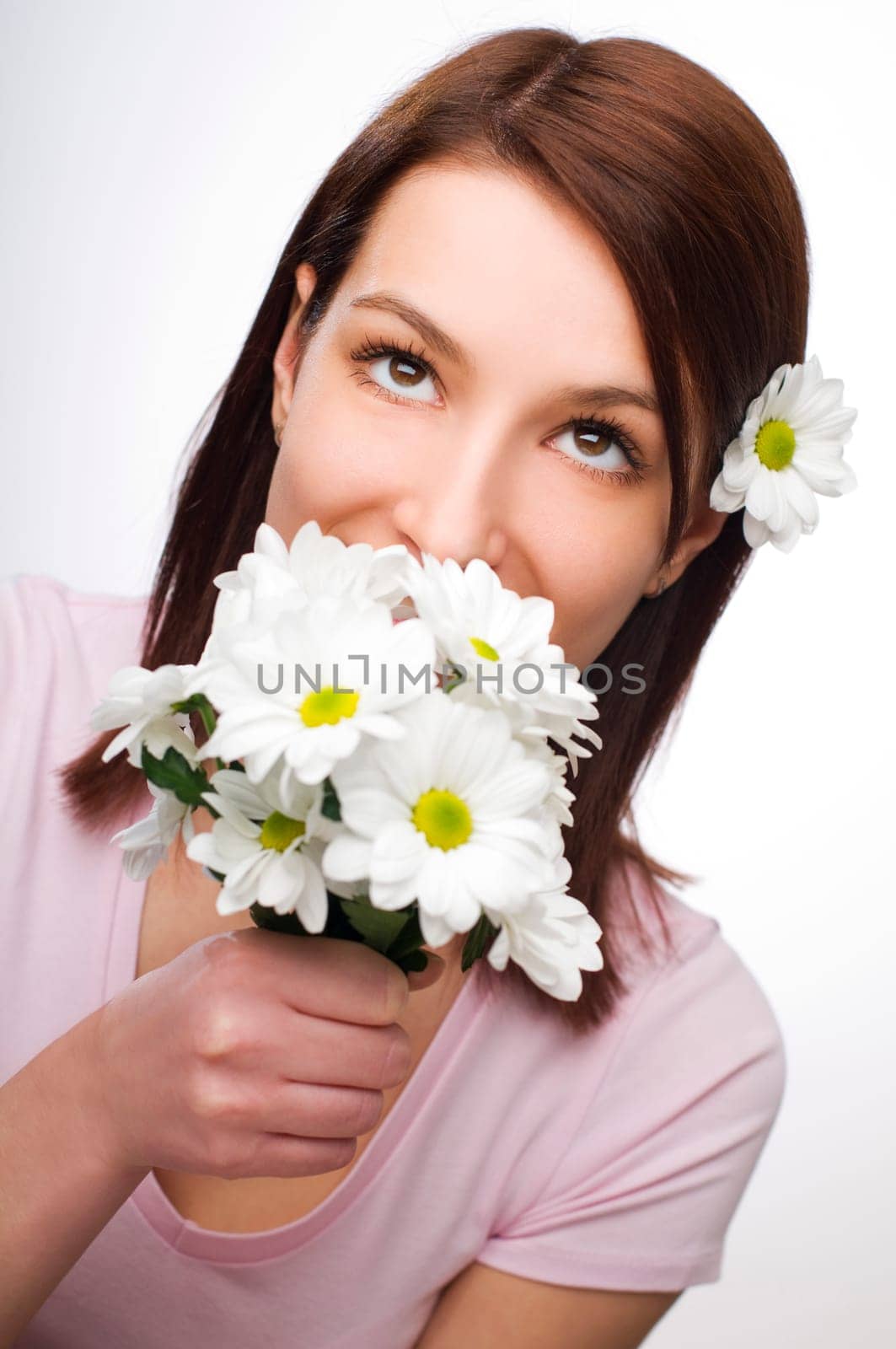 Beautiful young woman smelling flowers close up