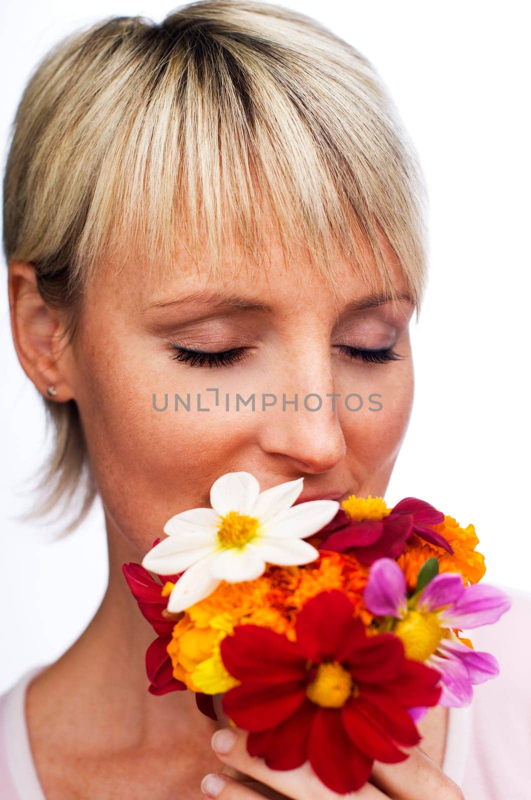 young blond woman smelling flowers close up