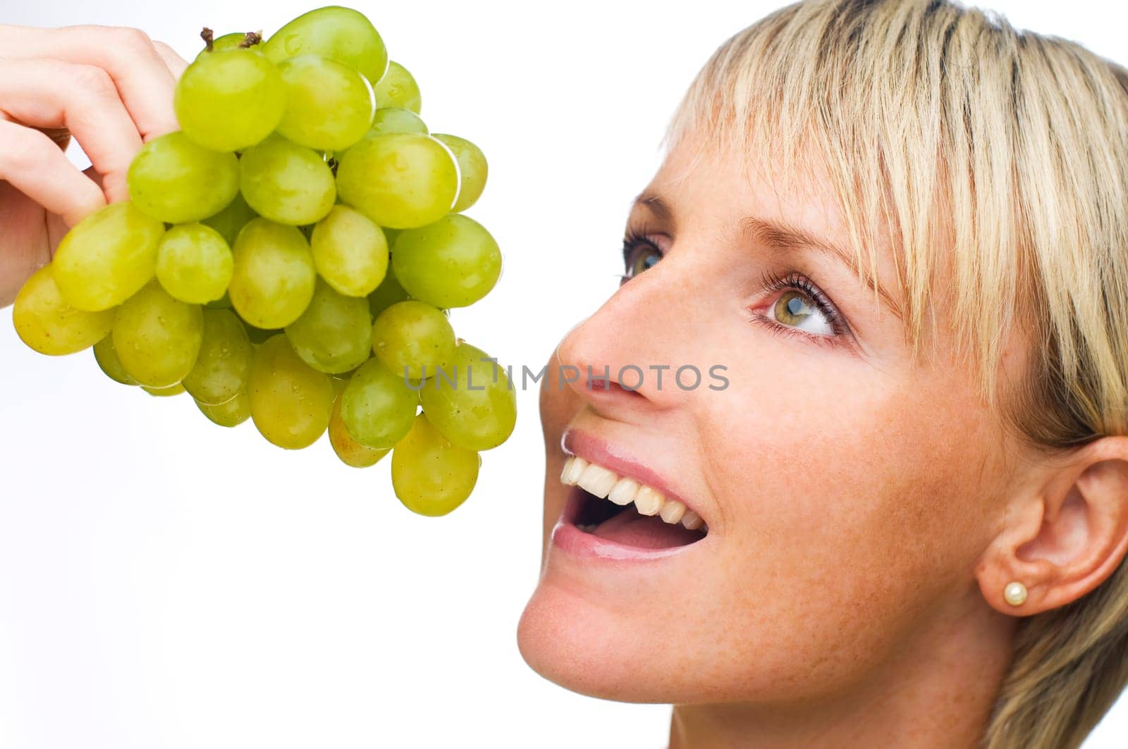 young blond woman eating green grape close up