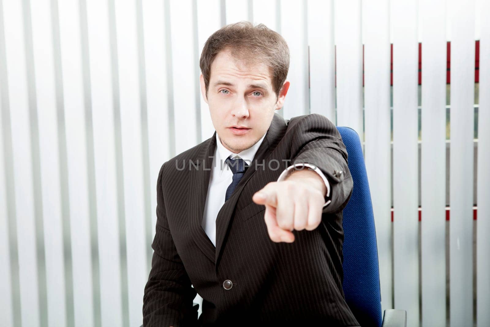 Businessman pointing a finger singling out a specific person to delegate work or to lay blame, indicating his choice or identifying somebody