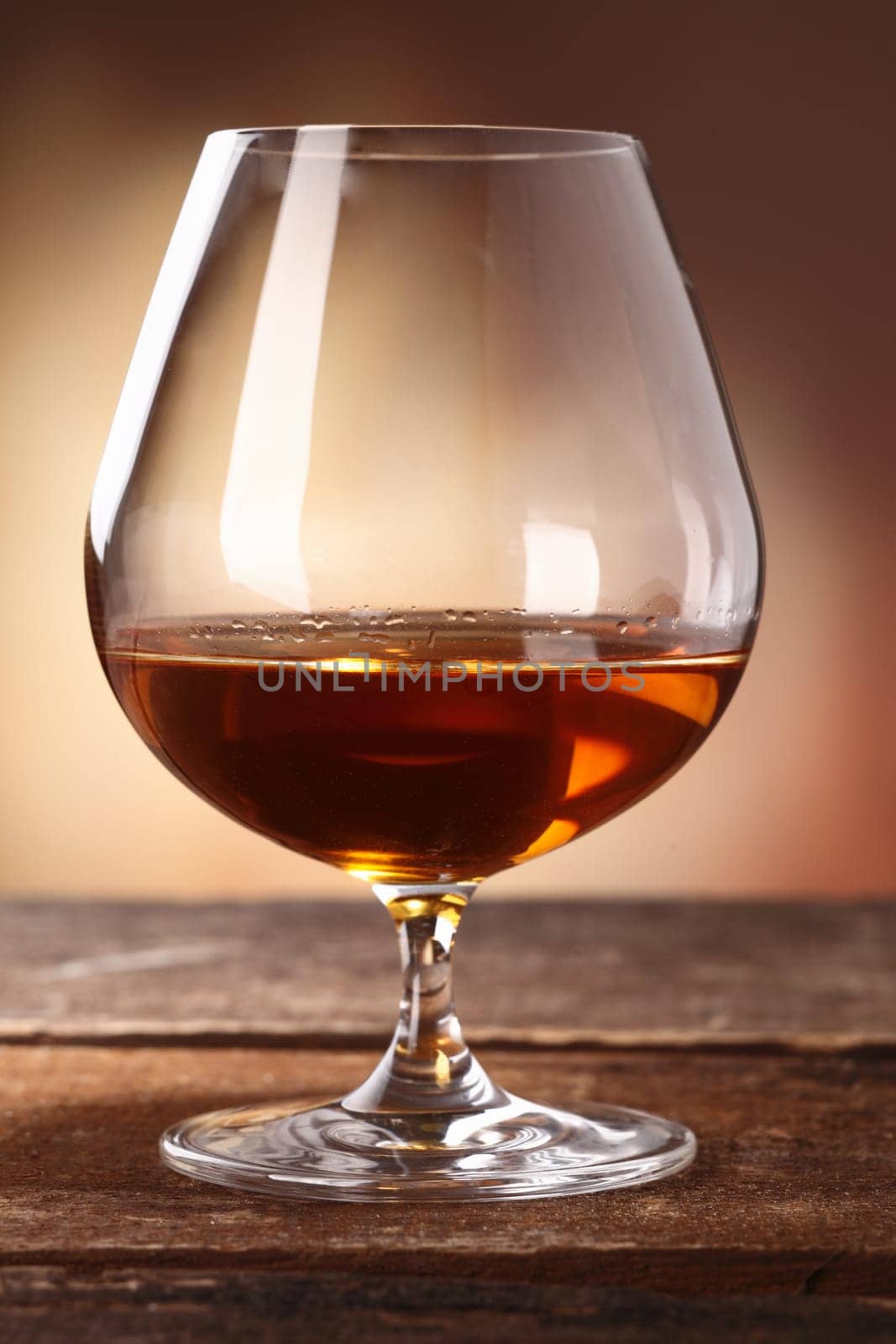 Glowing golden brown cognac served in a snifter as a luxury after dinner beverage