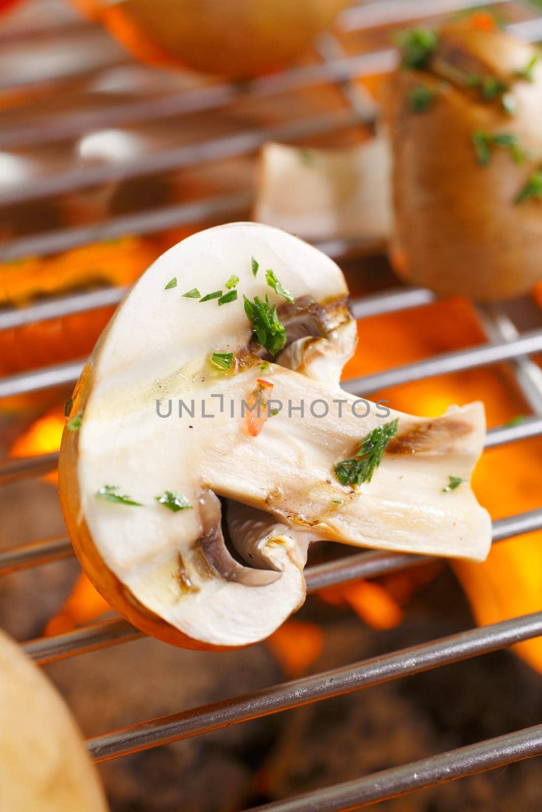 Fresh halved mushrooms sprinkled with chopped herbs for flavouring grilling over a barbecue fire