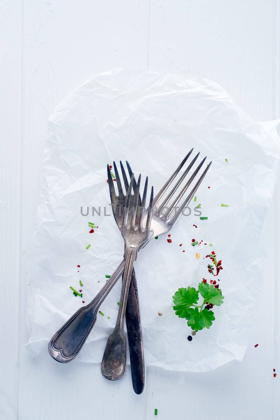 Top view of an empty plate with cutlery and sprigs of parsley.