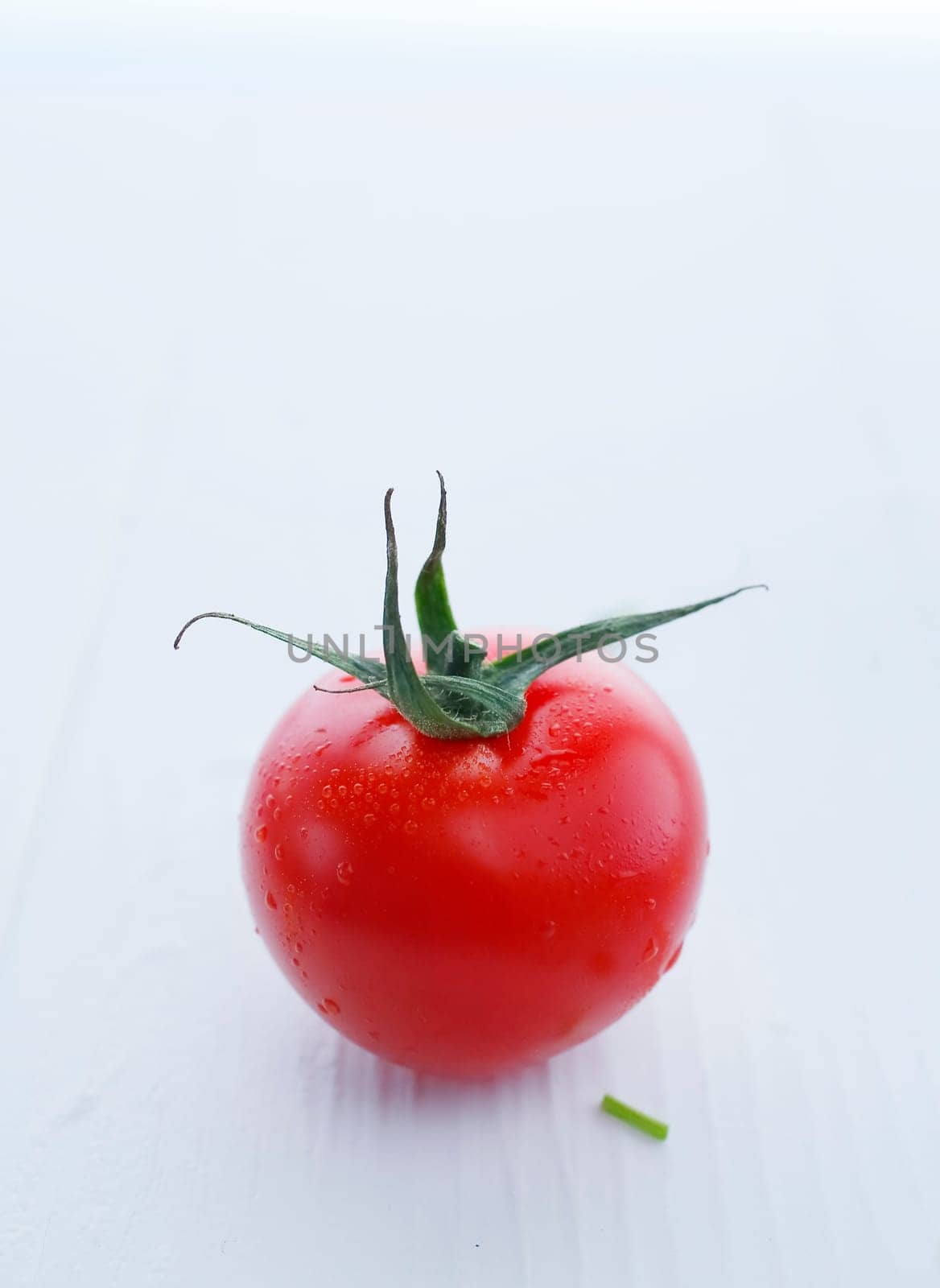 Gorgeous red tomato with stem, shallow depth of field shot against white.