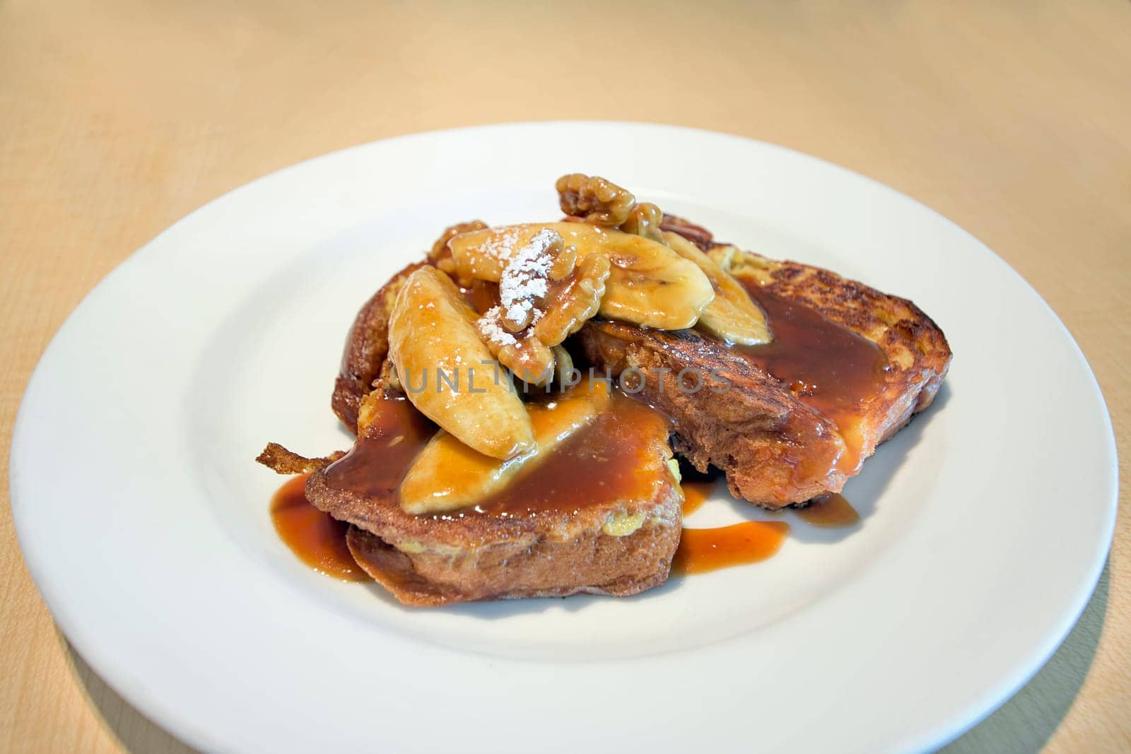 French Toast with Sliced Bananas Walnuts Powdered Sugar and Caramel Sauce Breakfast Dish