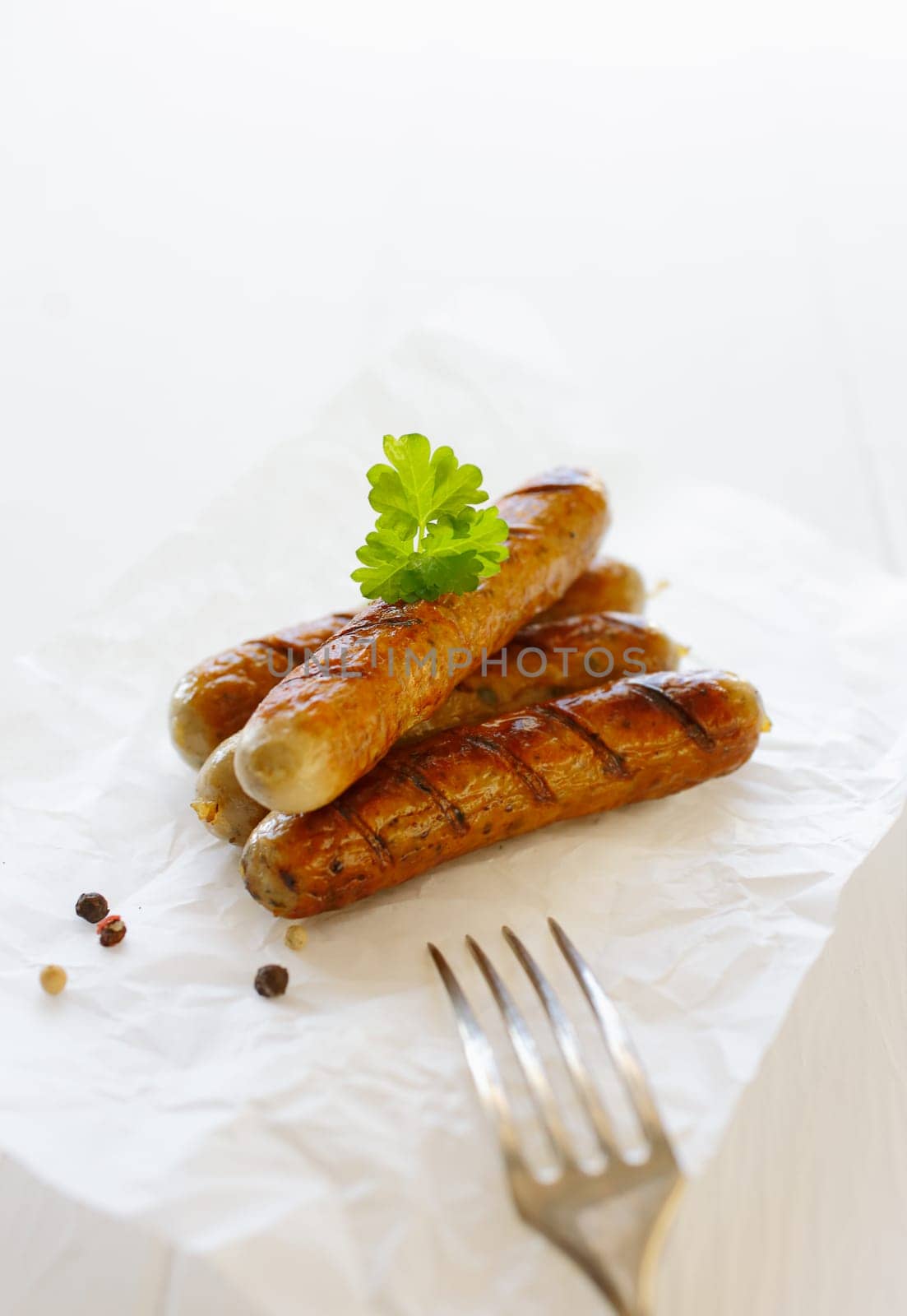 Grilled smoked bratwurst and fork against the white background
