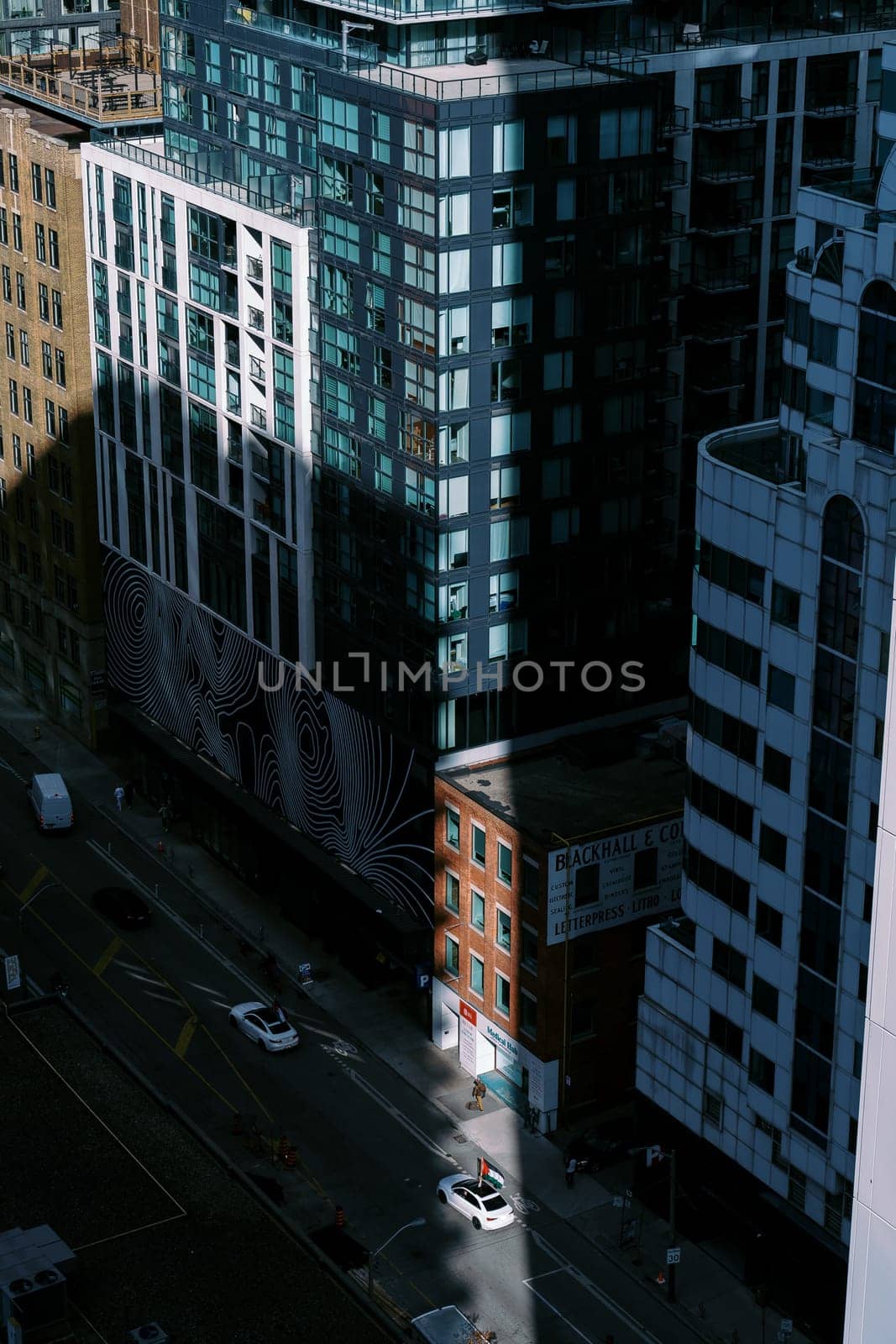 Aerial view of city streets with a blend of modern skyscrapers and traditional buildings, highlighted by sun rays amidst shadows. High quality photo