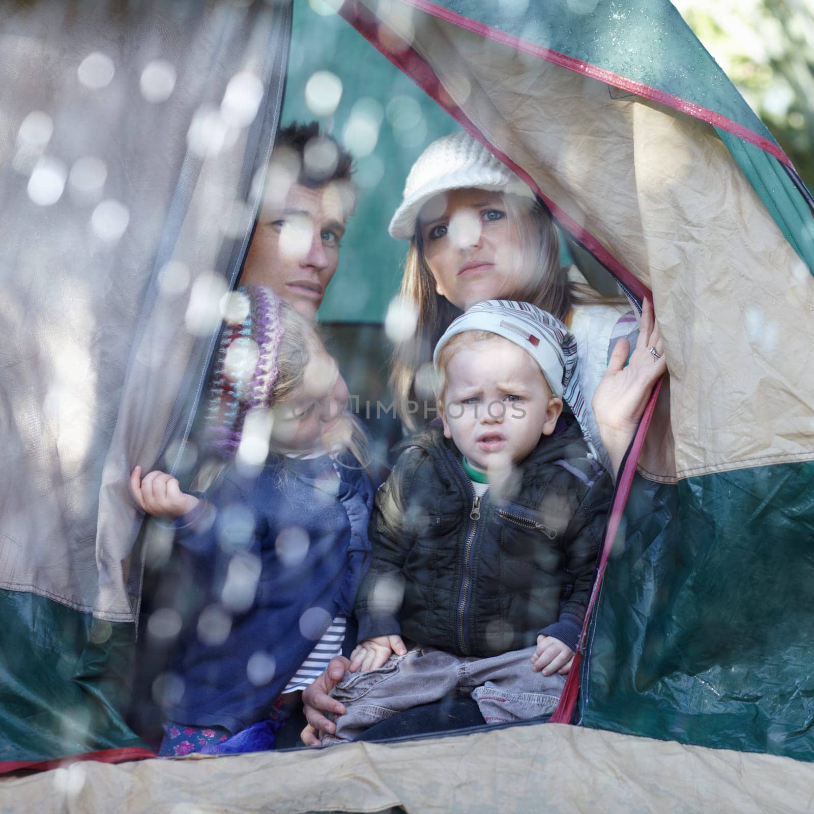 Camping, family and parents with children in rain sad for adventure, holiday and vacation in winter outdoors. Disappointed, unhappy and mother, father and kids in tent with bad weather for travel.