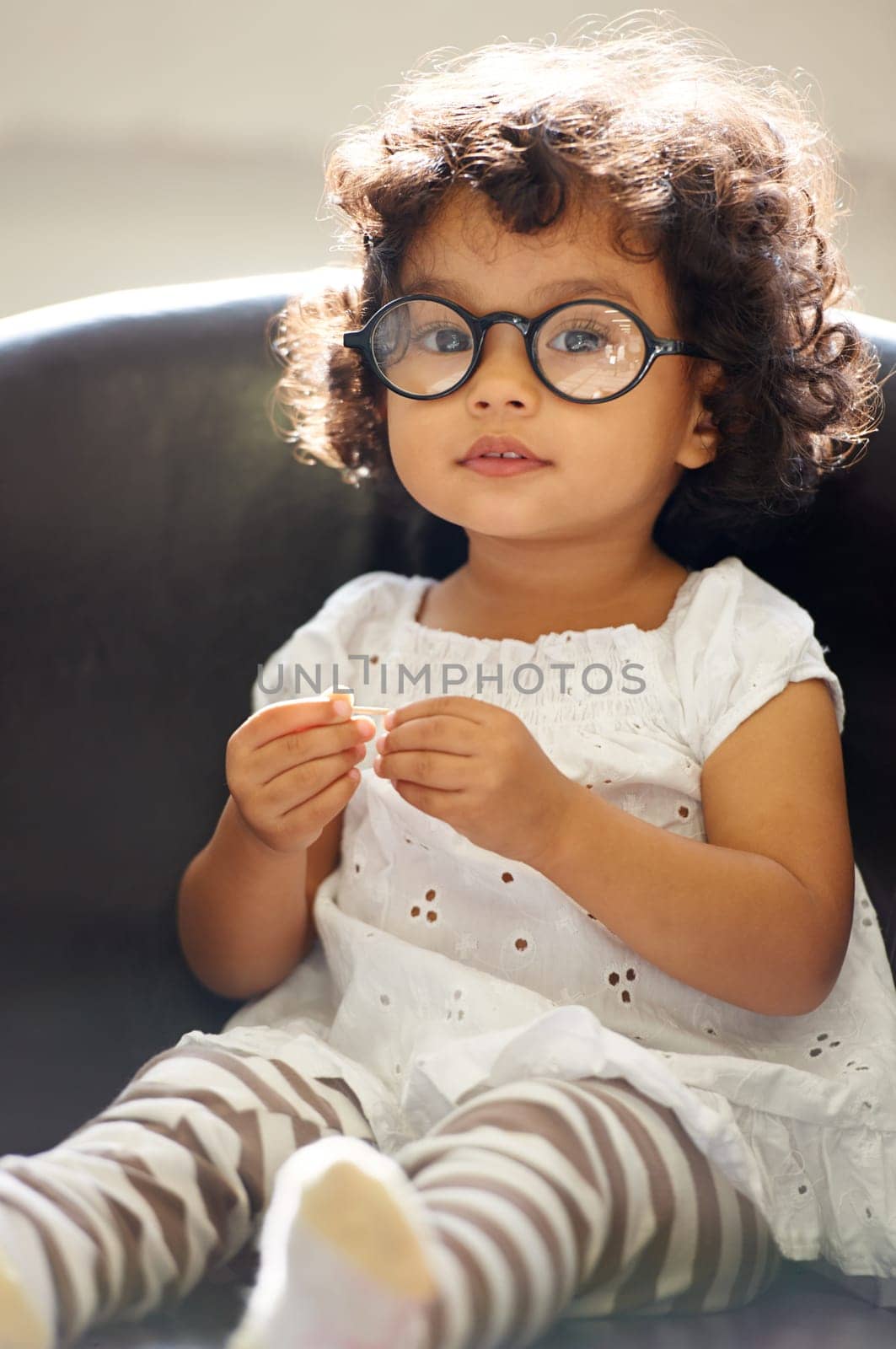 Girl, child and portrait or glasses for play, learning development or education growth. Female person, toddler and face eyewear on sofa in home for comedy outfit as professional, intelligence or fun.