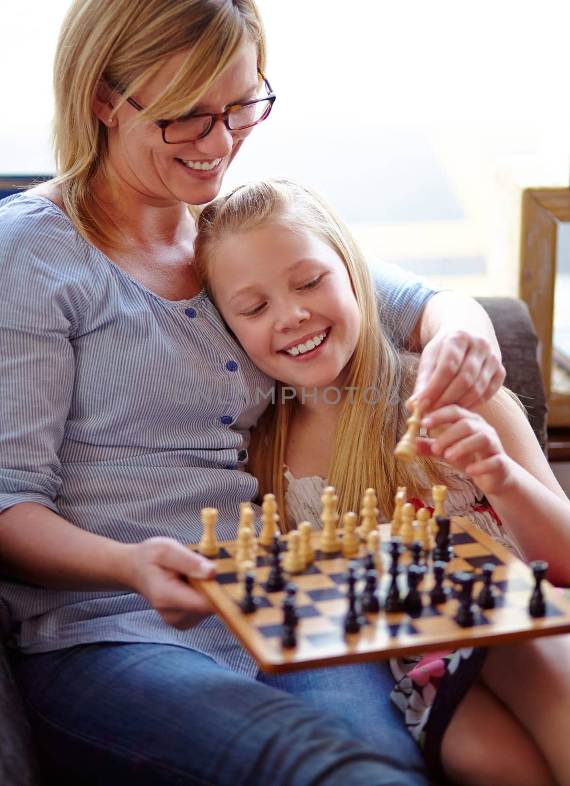 Happy, chess and a mother and child with a game for competition, strategy or thinking. Smile, family and a mom, girl or kid on a home sofa with a board for gaming, education and learning a hobby.