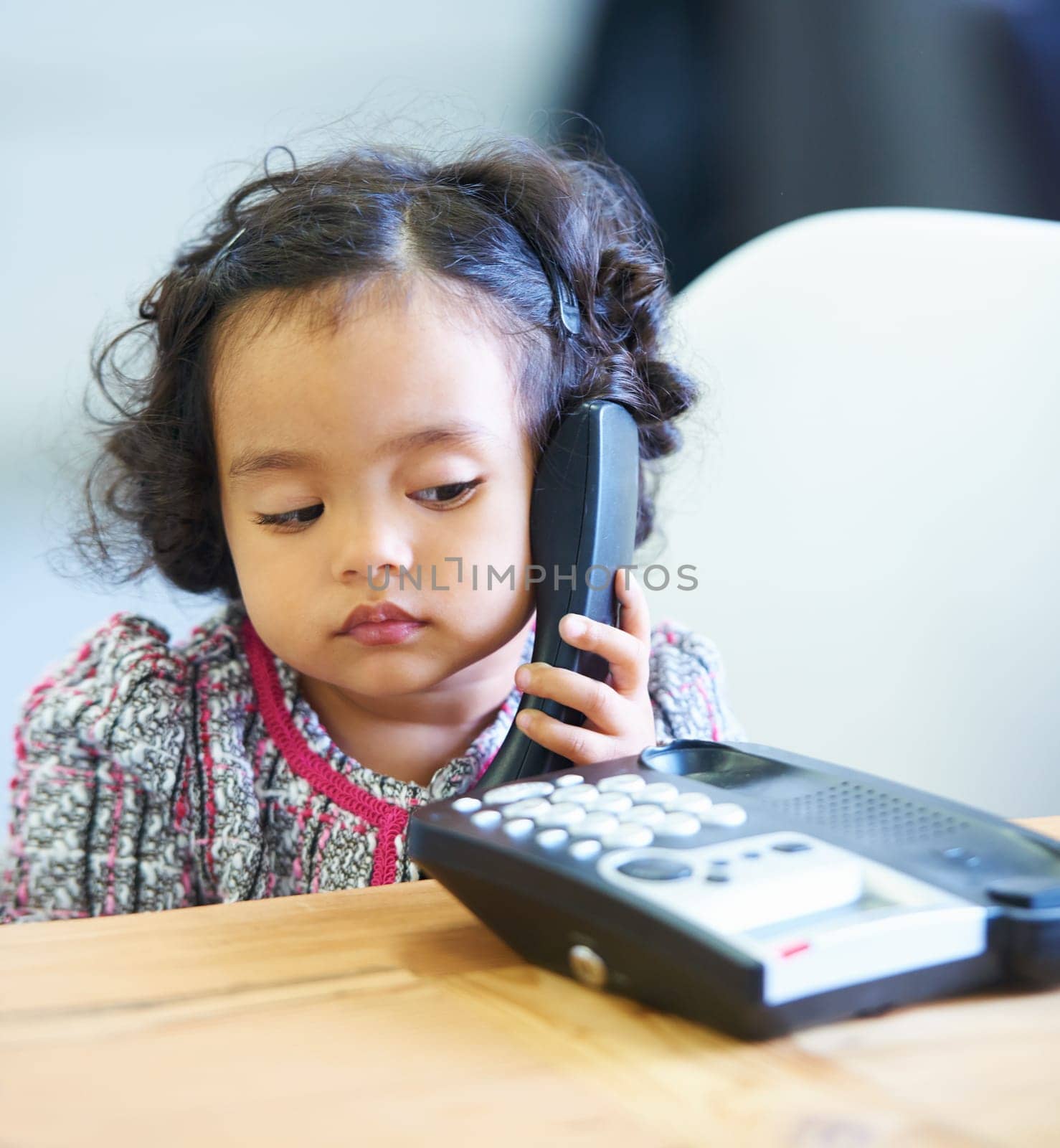 Listening, talking and a child on a telephone phone call for communication in a house. Home, contact and a girl, kid or baby speaking on a landline for conversation, play or a discussion at a desk by YuriArcurs