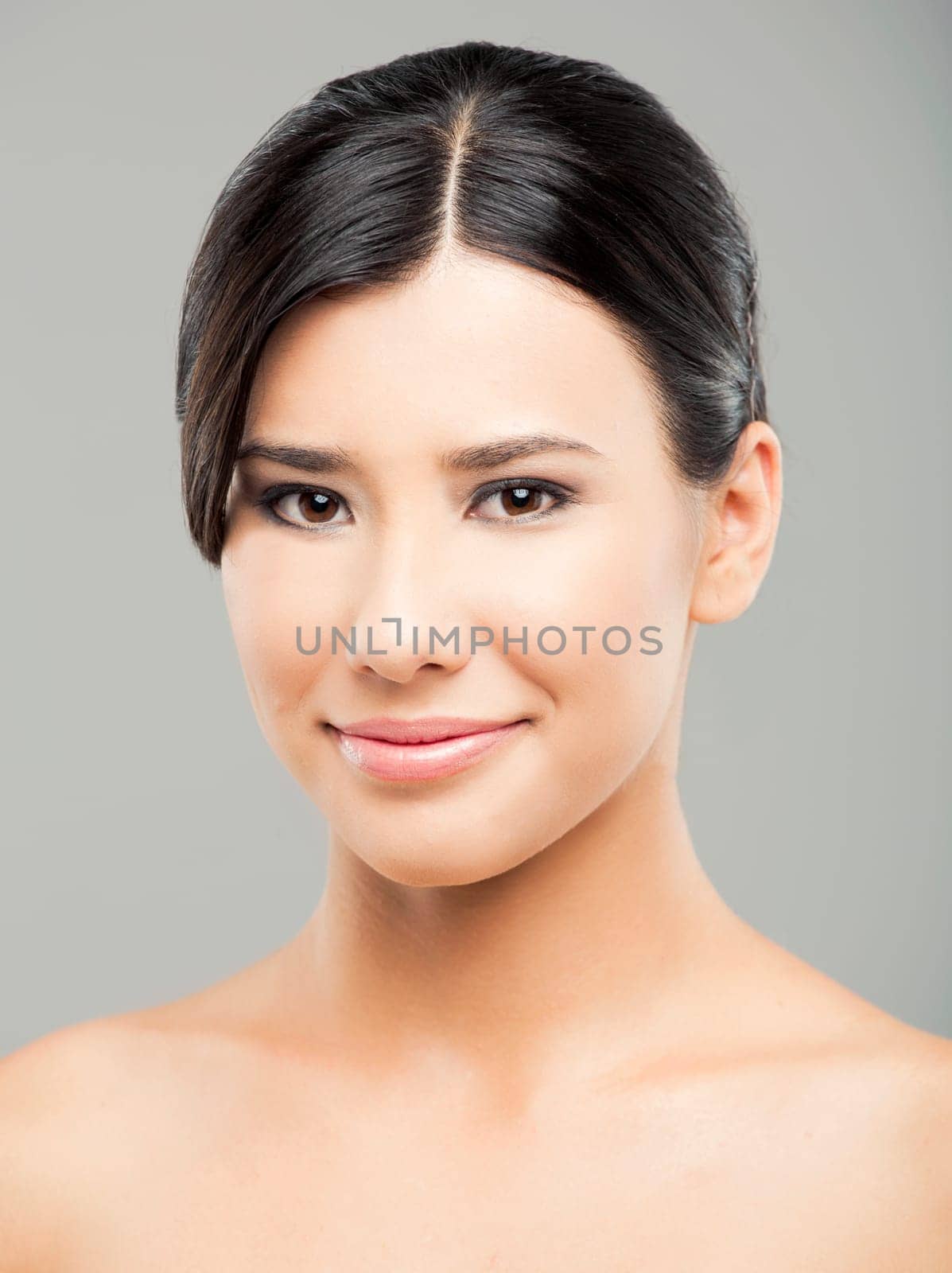 Beauty portrait of young asian woman smiling, over a gray background.